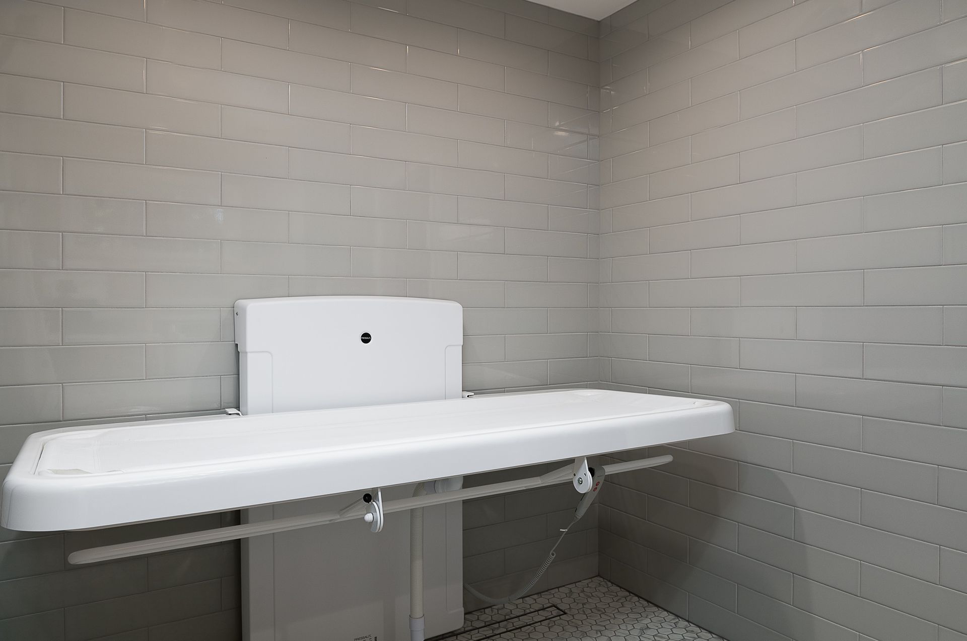 A bathroom with a changing table attached to the wall.