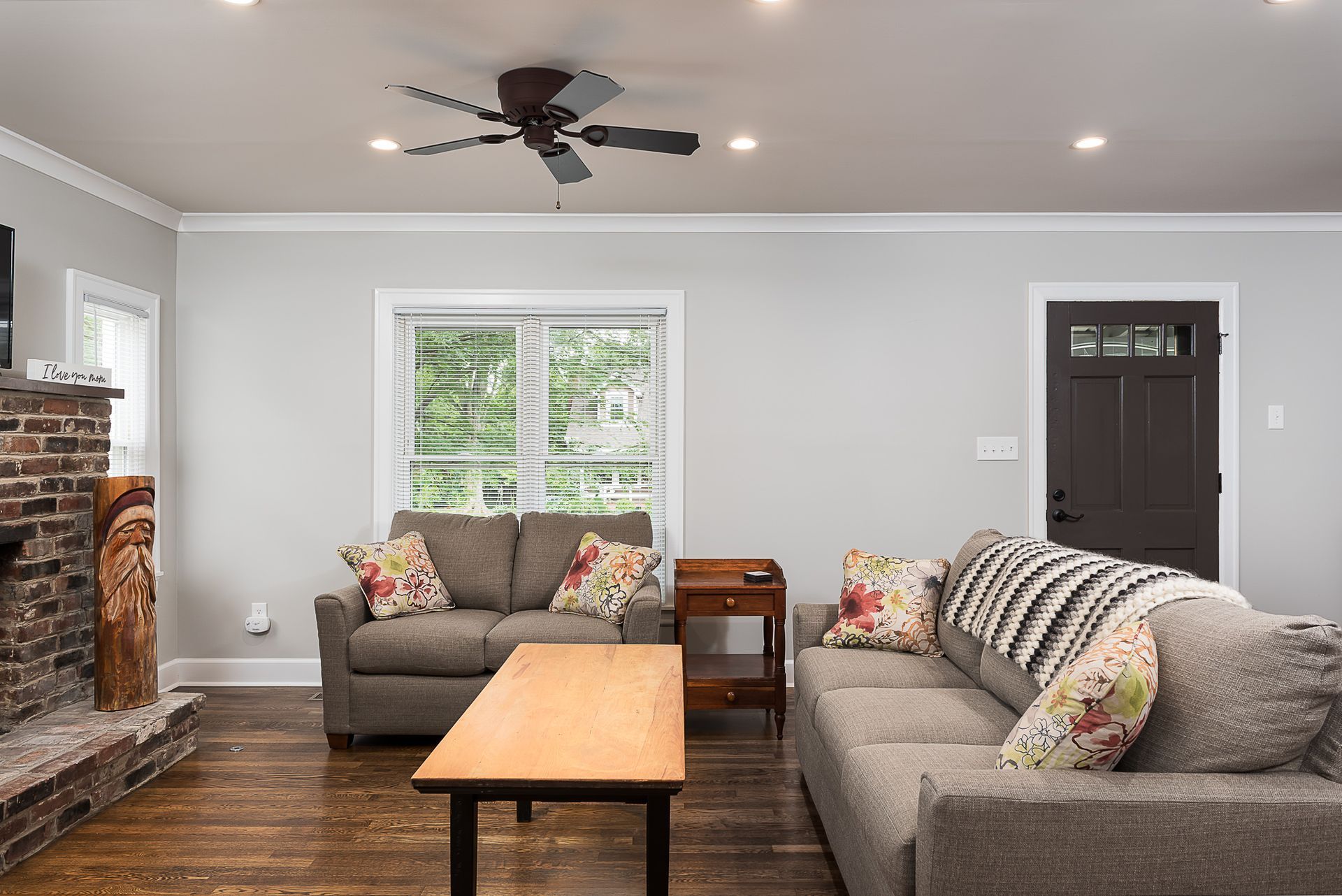 A living room with a couch , coffee table , fireplace and ceiling fan.