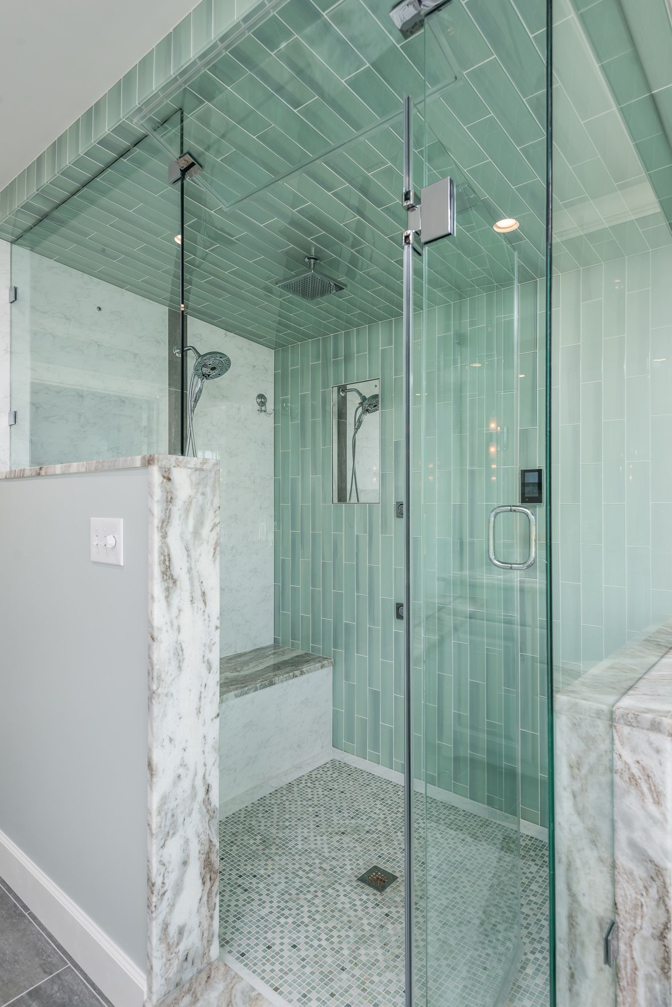 A bathroom with a walk in shower with a glass door.