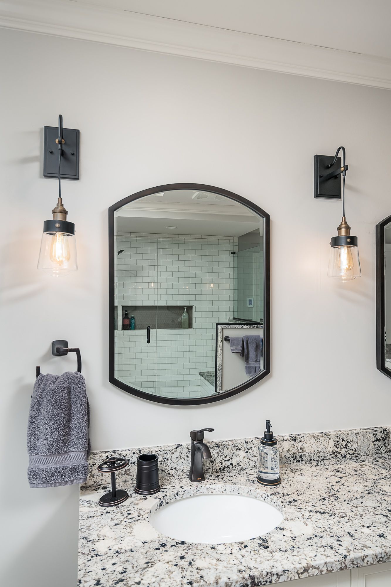 A bathroom with a sink and two mirrors on the wall.