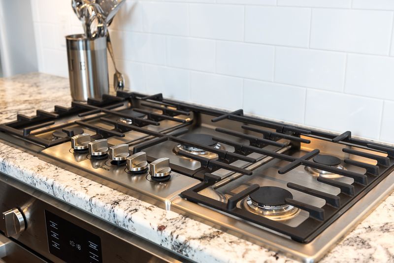 A stove top oven is sitting on top of a granite counter in a kitchen.