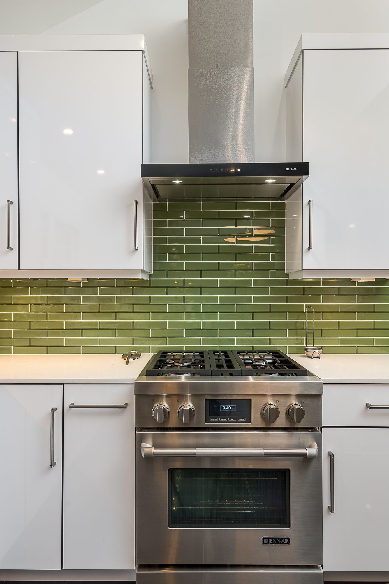 A kitchen with stainless steel appliances and green tiles