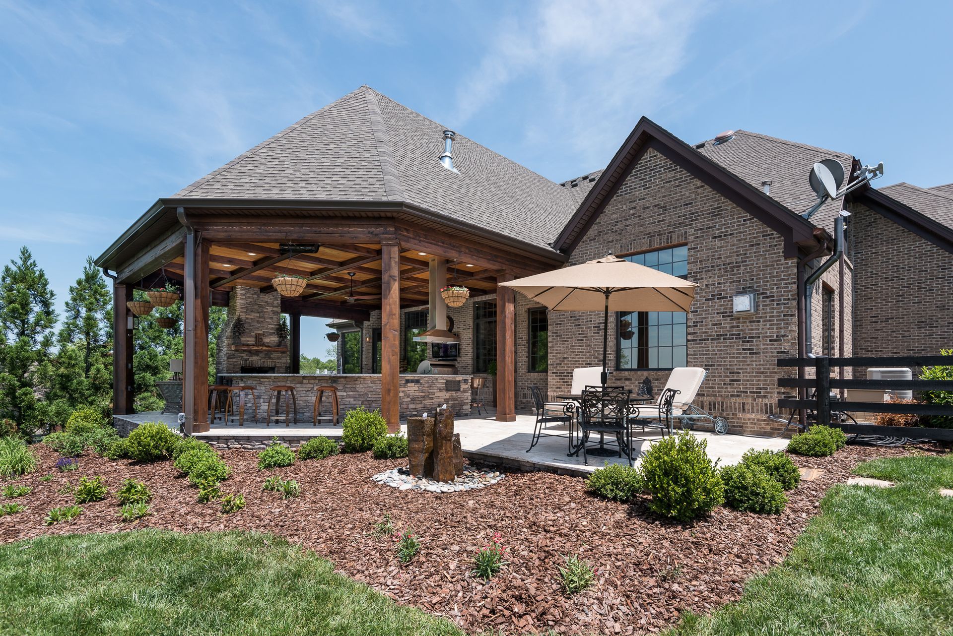 A large brick house with a patio and umbrellas in front of it.