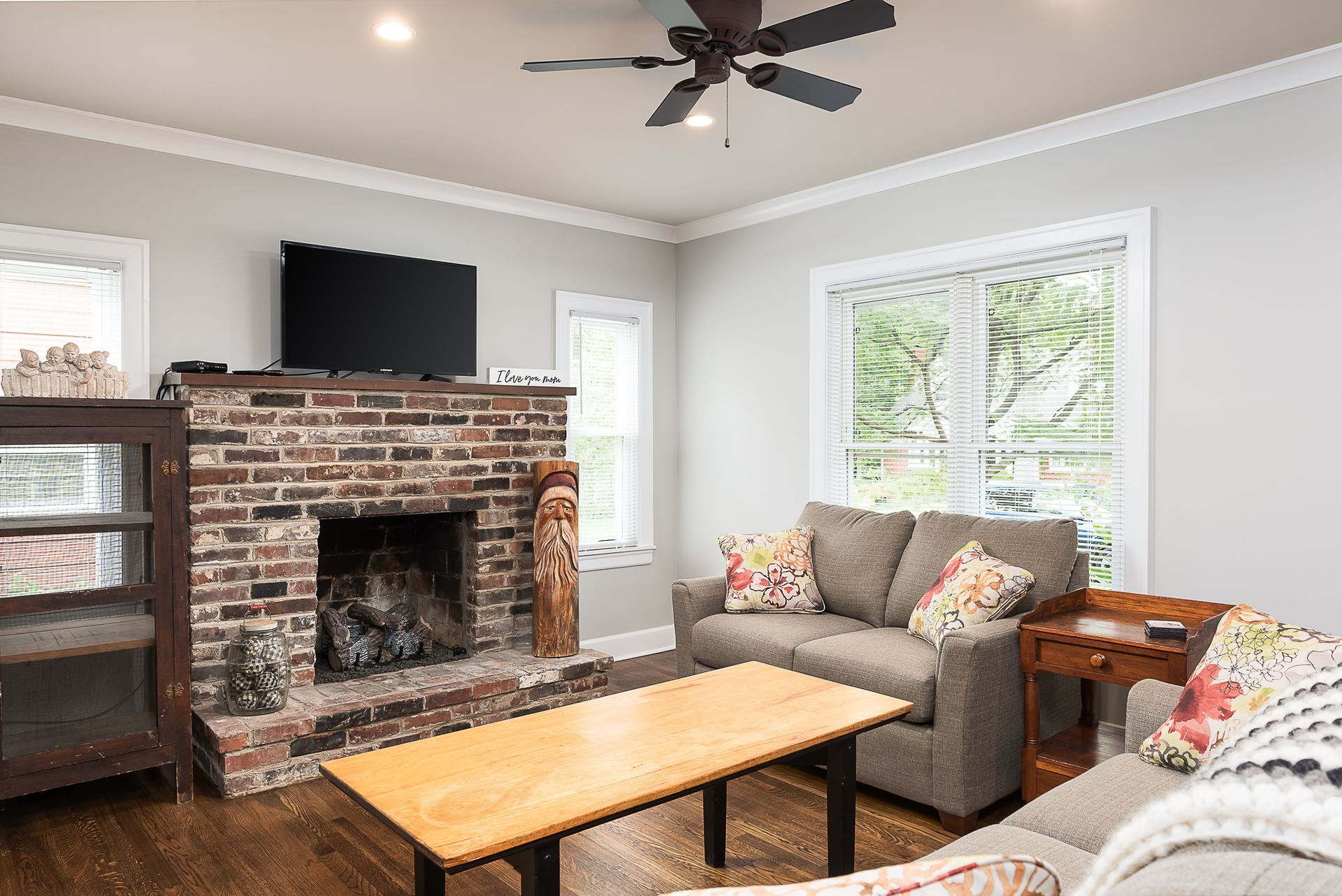 A living room with a couch , fireplace , television and ceiling fan.