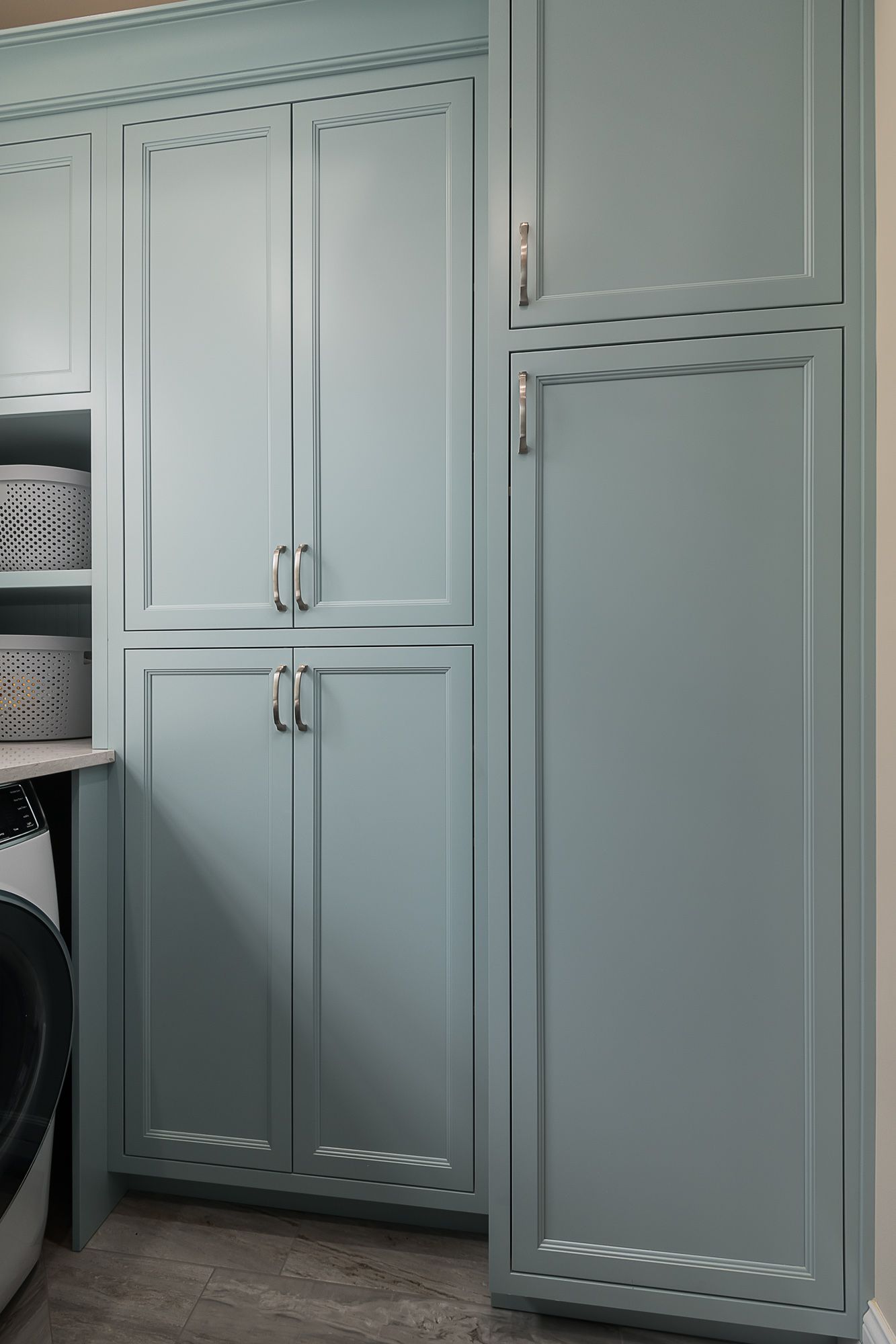 A laundry room with blue cabinets and a washer and dryer.
