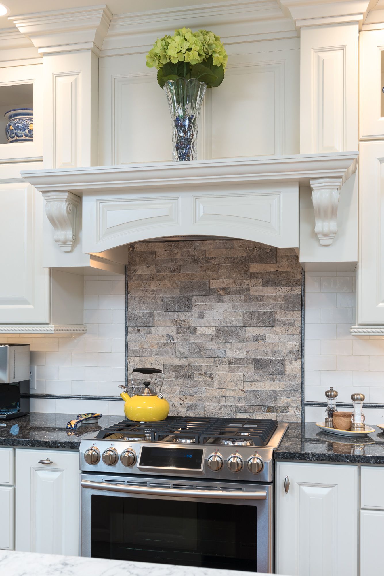 A kitchen with a stove top oven and a vase of flowers on the counter.