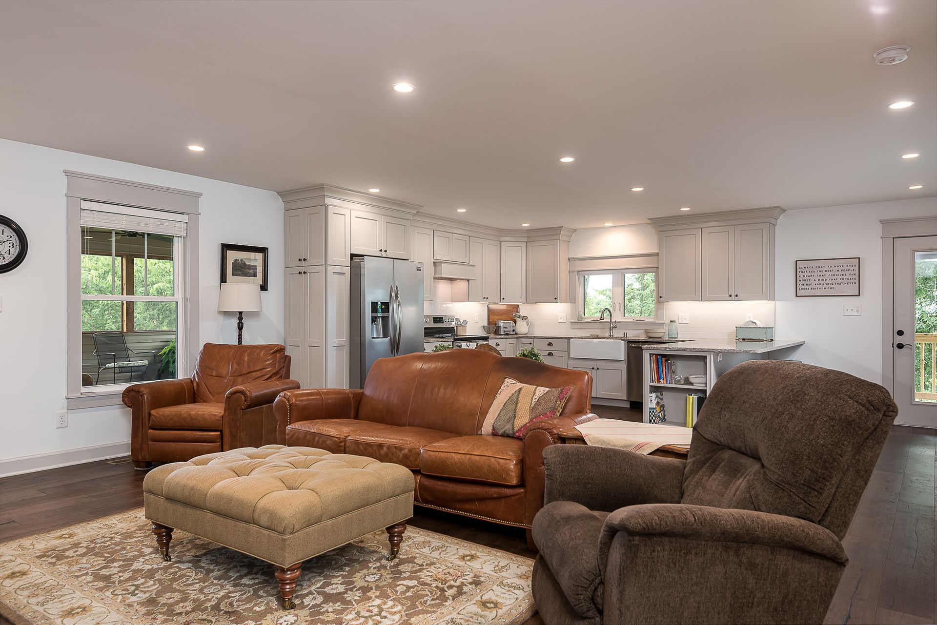 A living room with a couch , chairs , and ottoman.