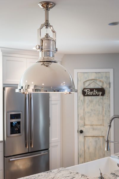 A kitchen with a stainless steel refrigerator and a pendant light hanging from the ceiling.