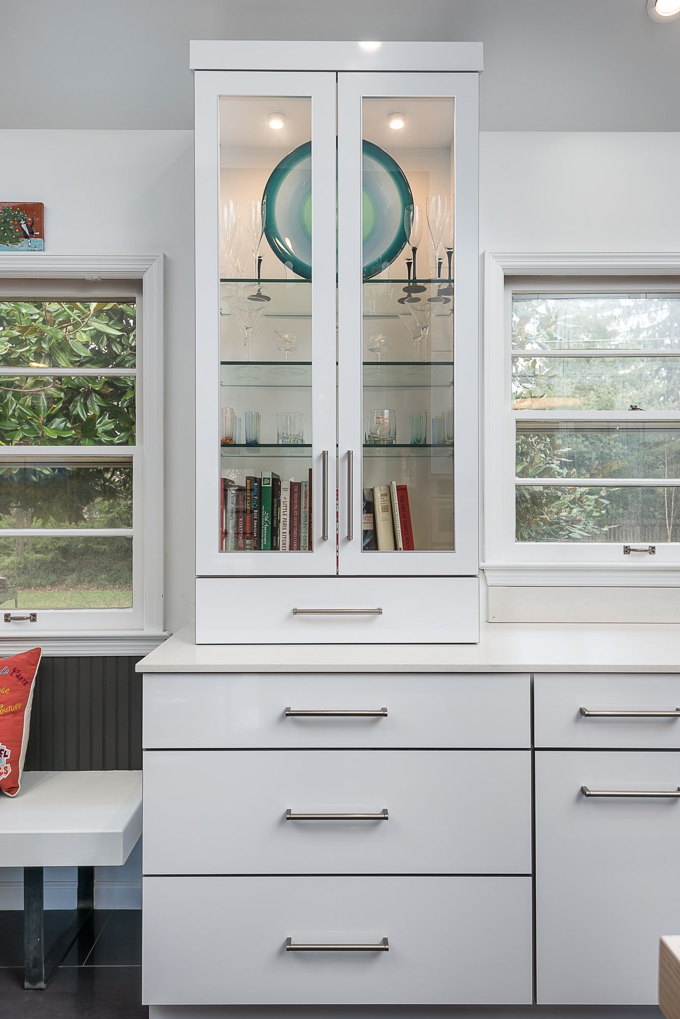 A white cabinet with glass doors and drawers in a kitchen