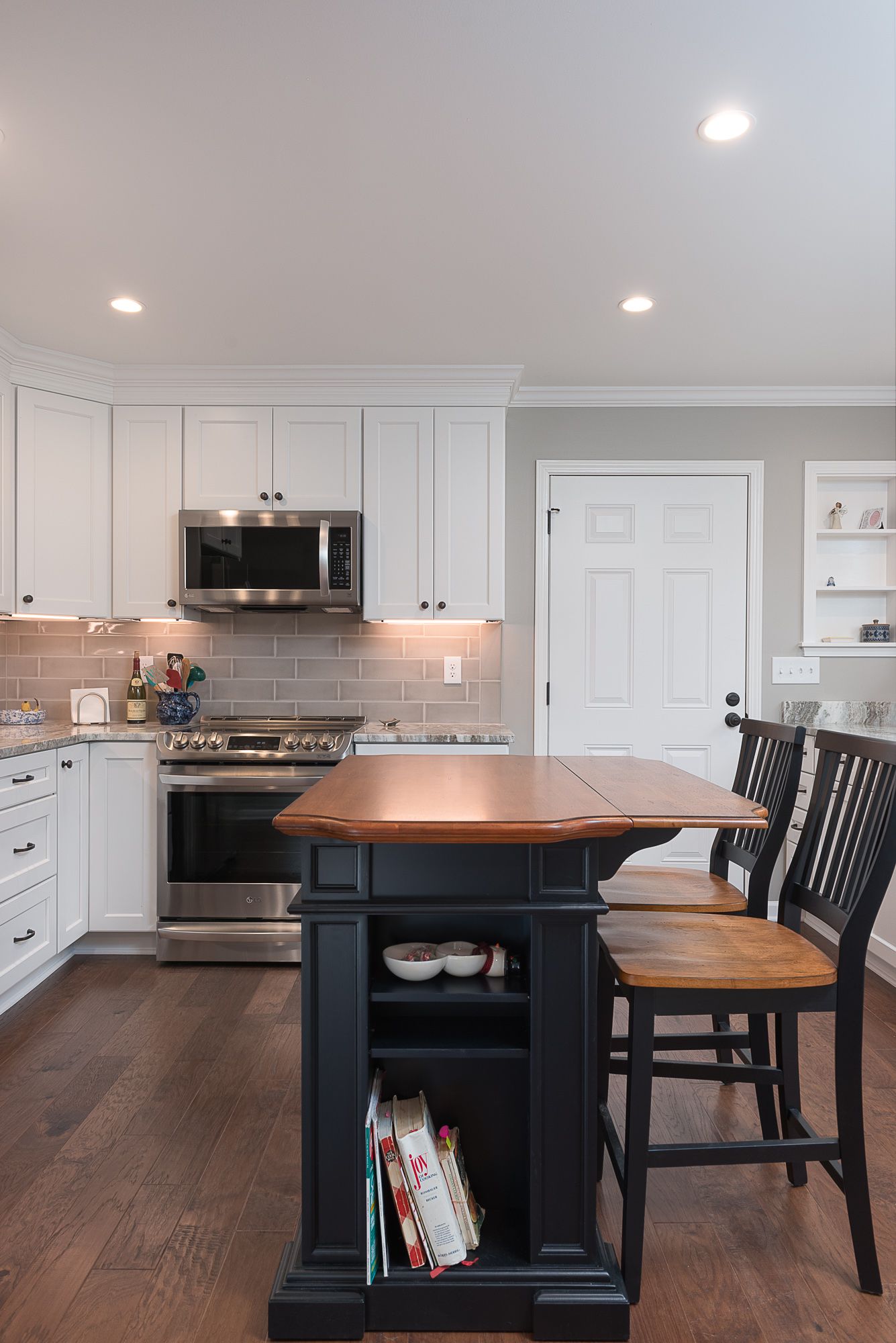 A kitchen with white cabinets , stainless steel appliances , a table and chairs.