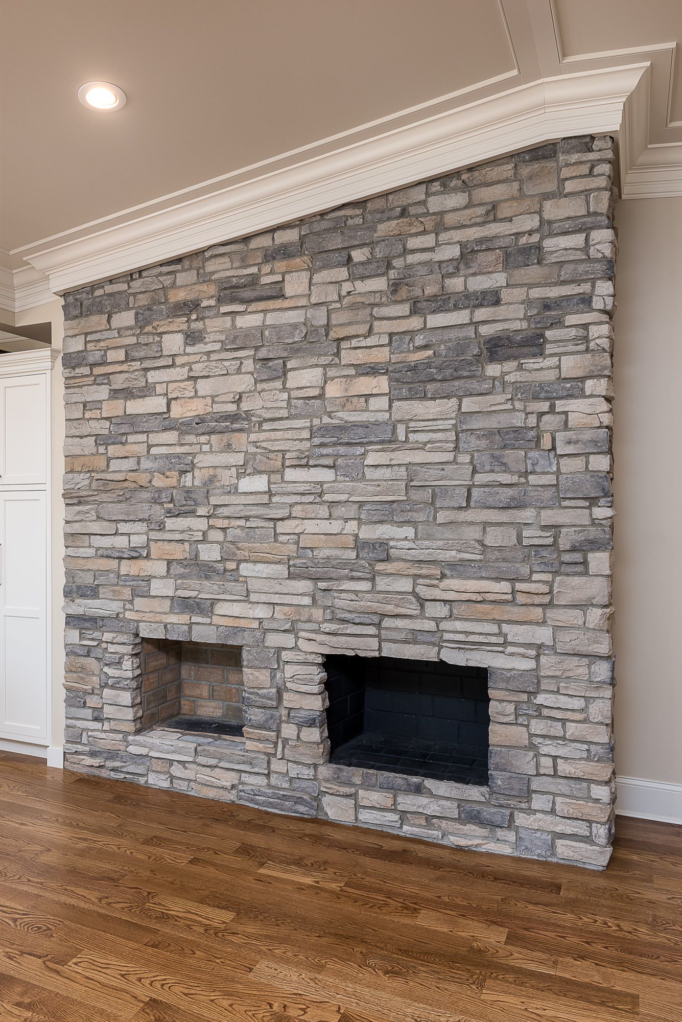 A large stone fireplace with a wooden floor in a living room.