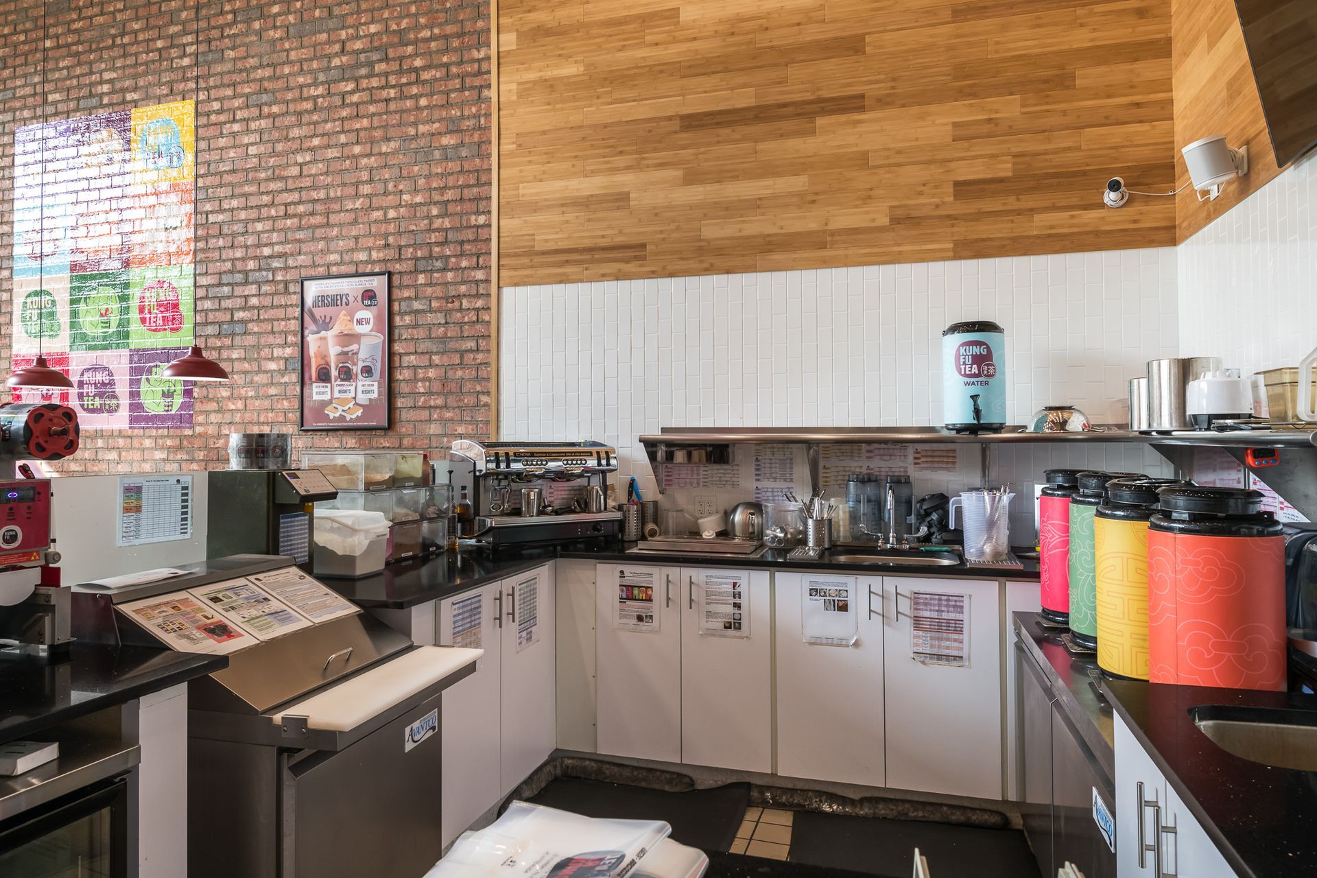 A kitchen in a restaurant with a brick wall and wooden ceiling.