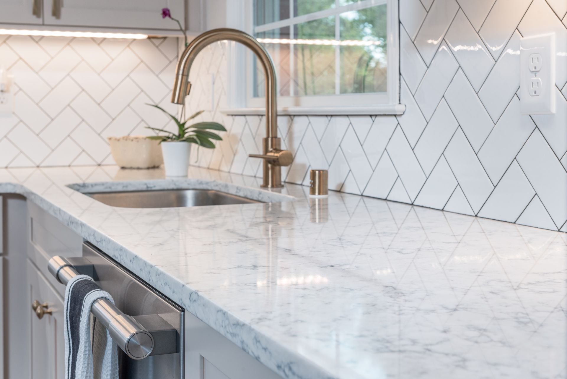 A kitchen with a sink , faucet , and marble counter tops.