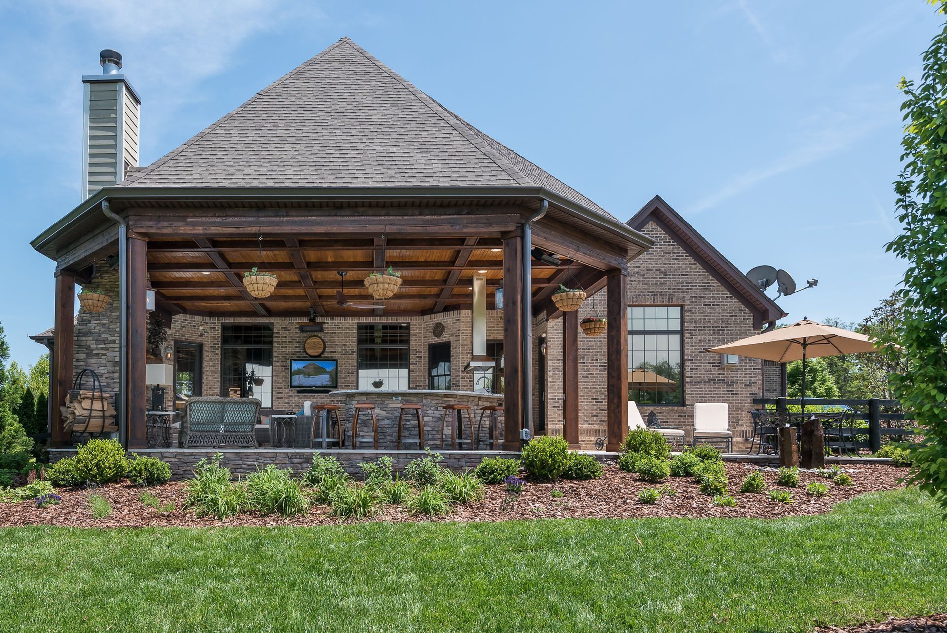 The back of a house with a large porch and umbrellas.