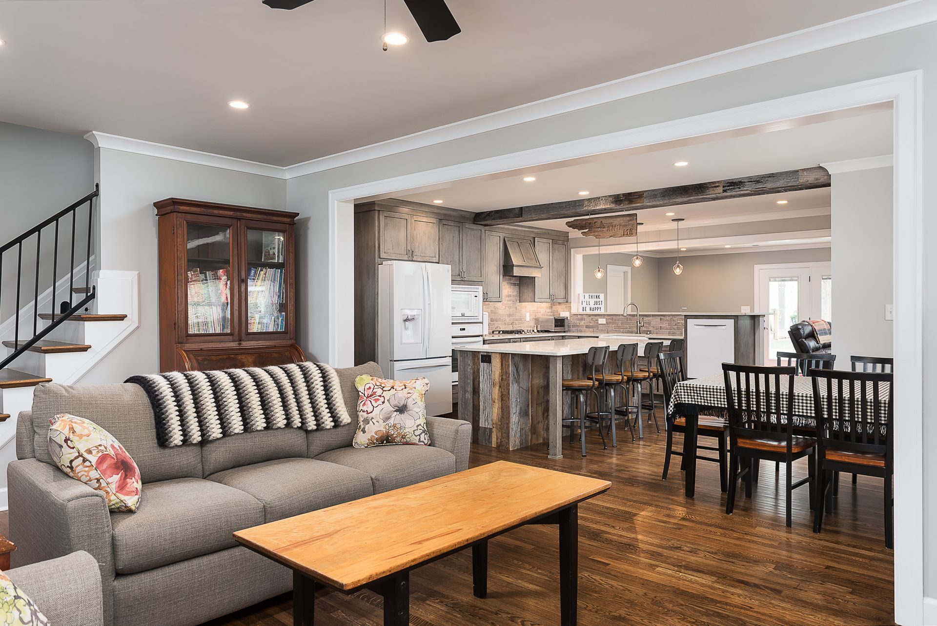 A living room with a couch , table , chairs and a ceiling fan.