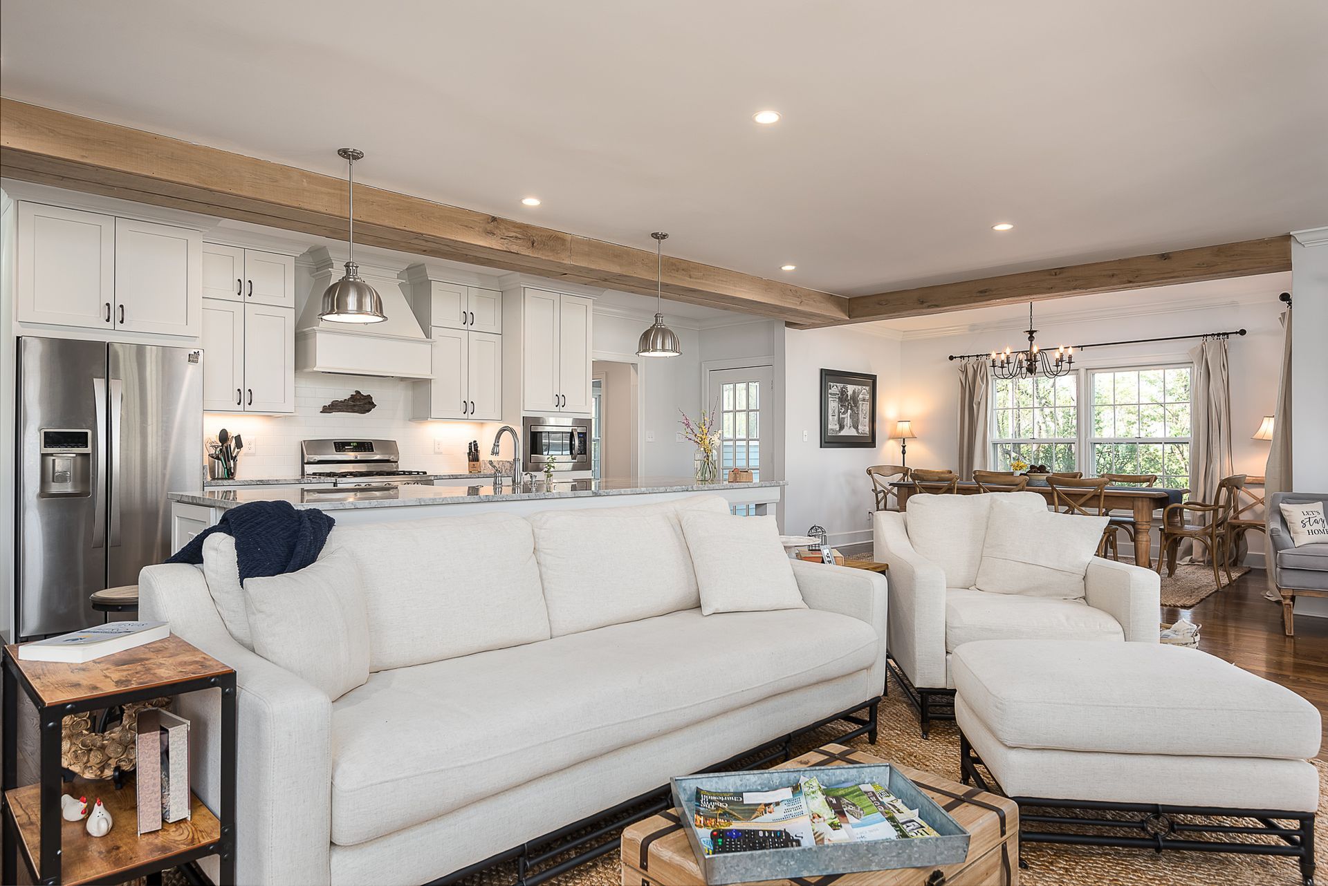 A living room with a white couch , chair , coffee table and ottoman.