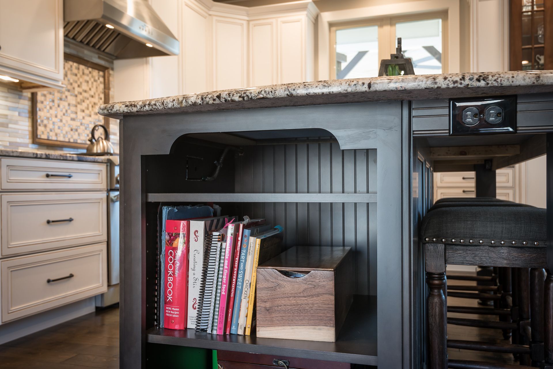 A kitchen island with a shelf filled with books.