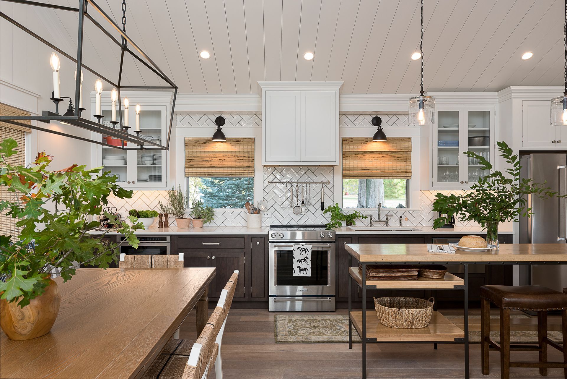 A kitchen with stainless steel appliances , a large island , a table and chairs.