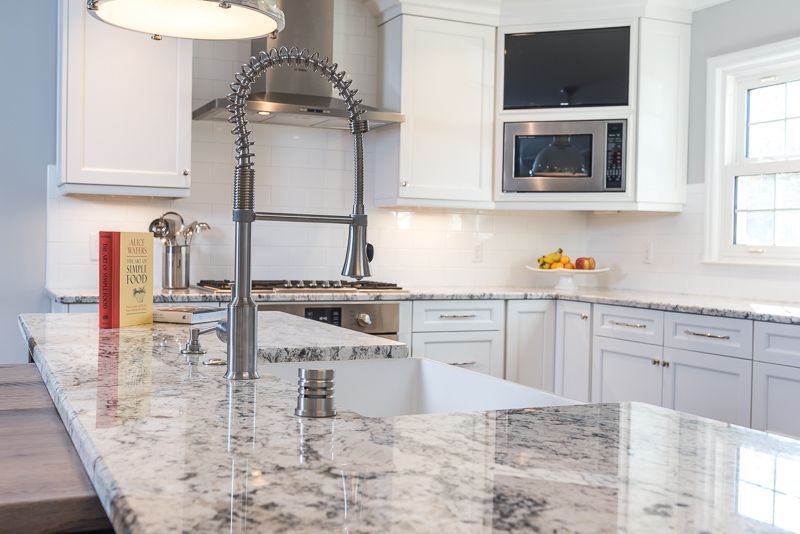 A kitchen with white cabinets and granite counter tops.