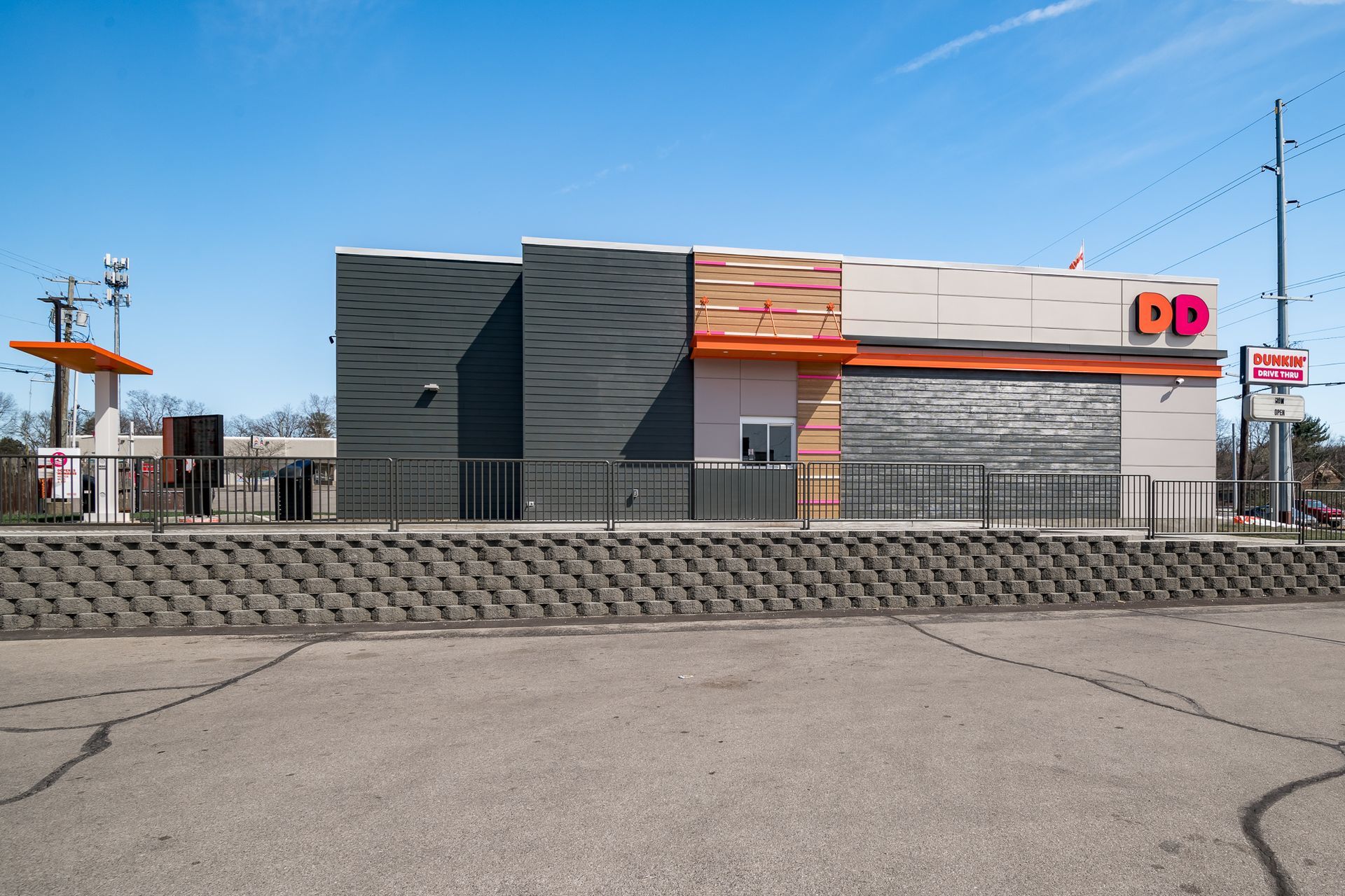 A dunkin donuts restaurant is sitting in an empty parking lot.