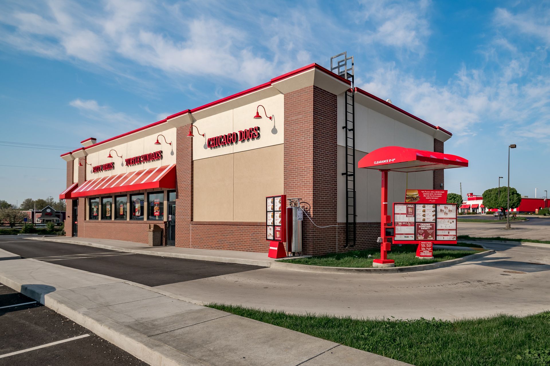 A fast food restaurant with a drive thru and a red awning