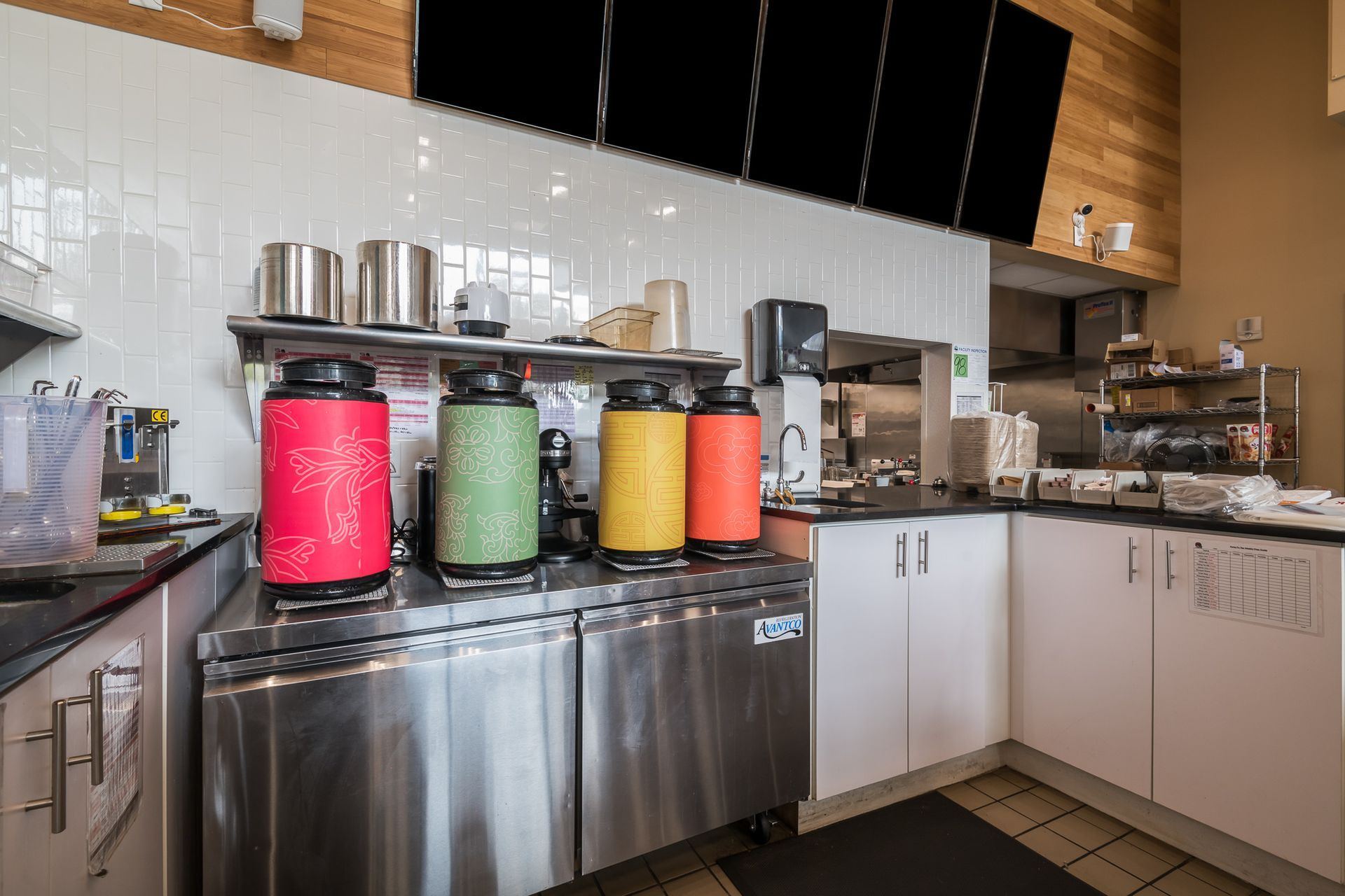A kitchen with a lot of stainless steel appliances and containers on the counter.