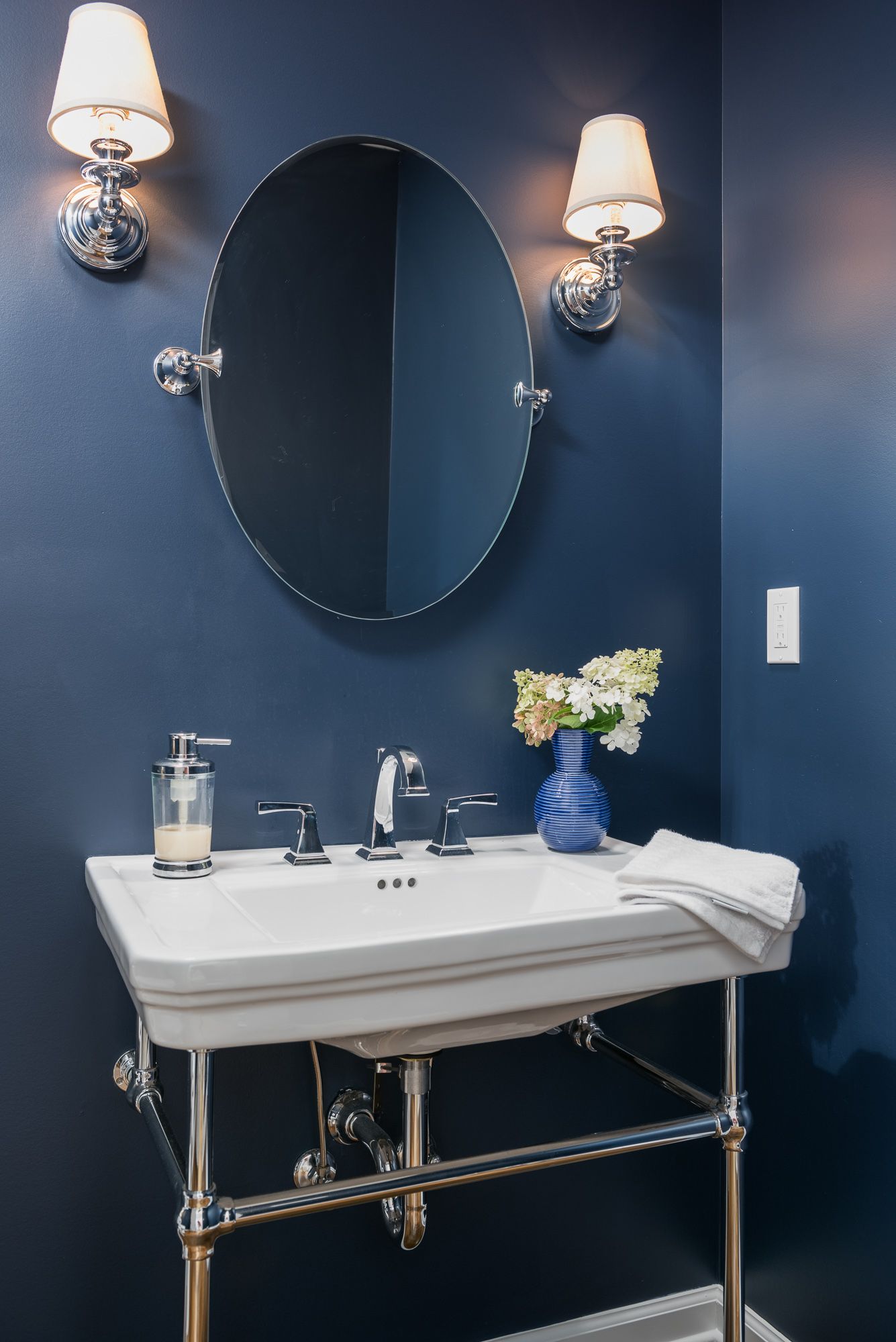 A bathroom with blue walls and a sink and mirror.