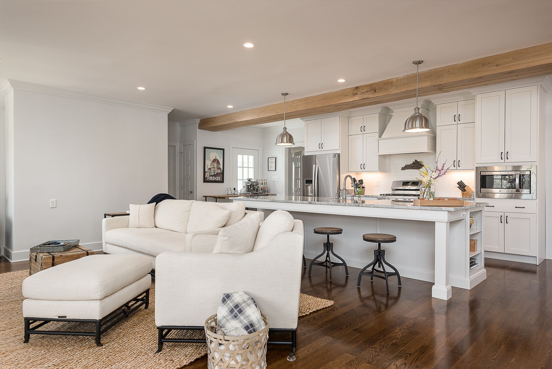 A living room with a couch , chair , ottoman , and kitchen.