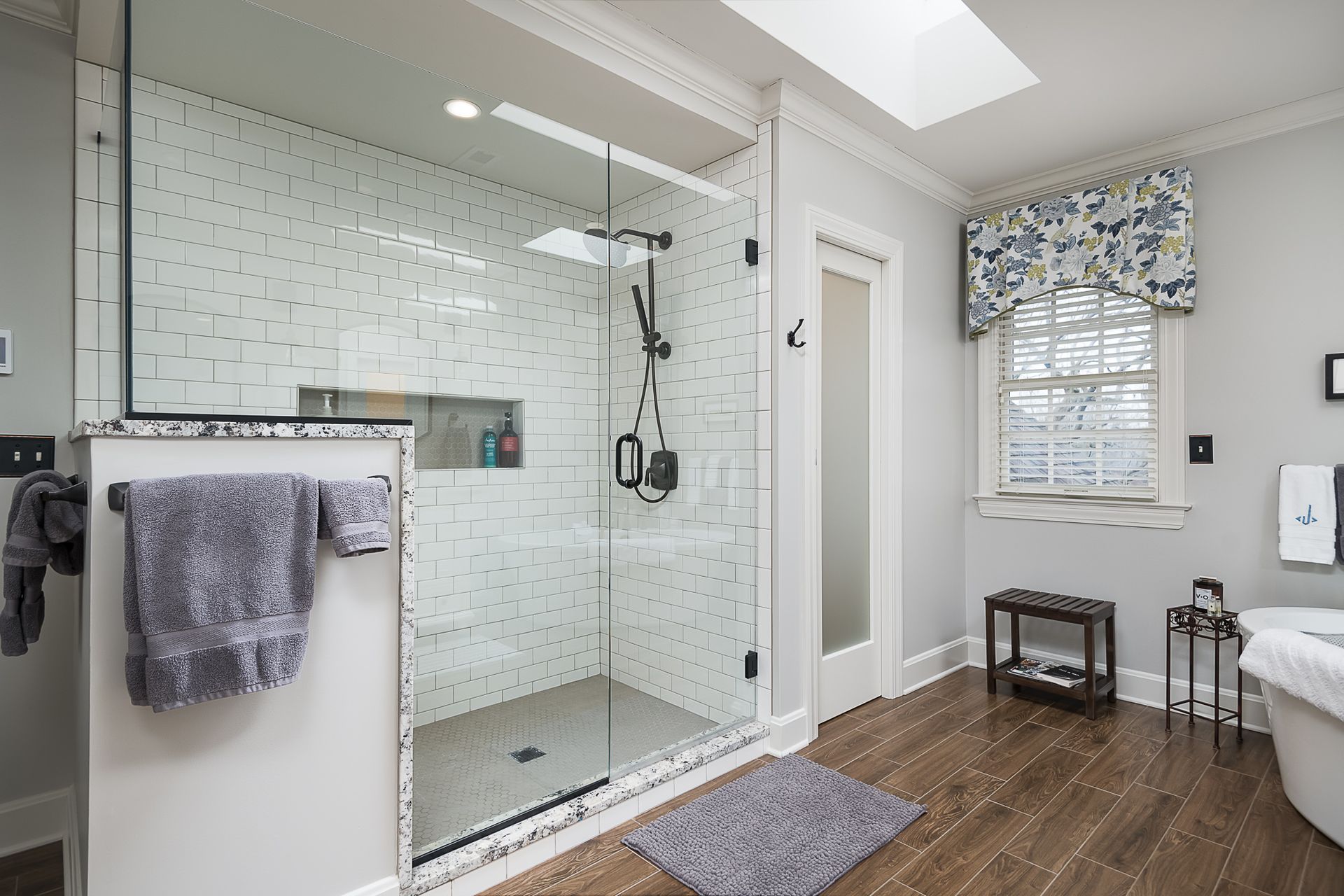 A bathroom with a walk in shower and a window.