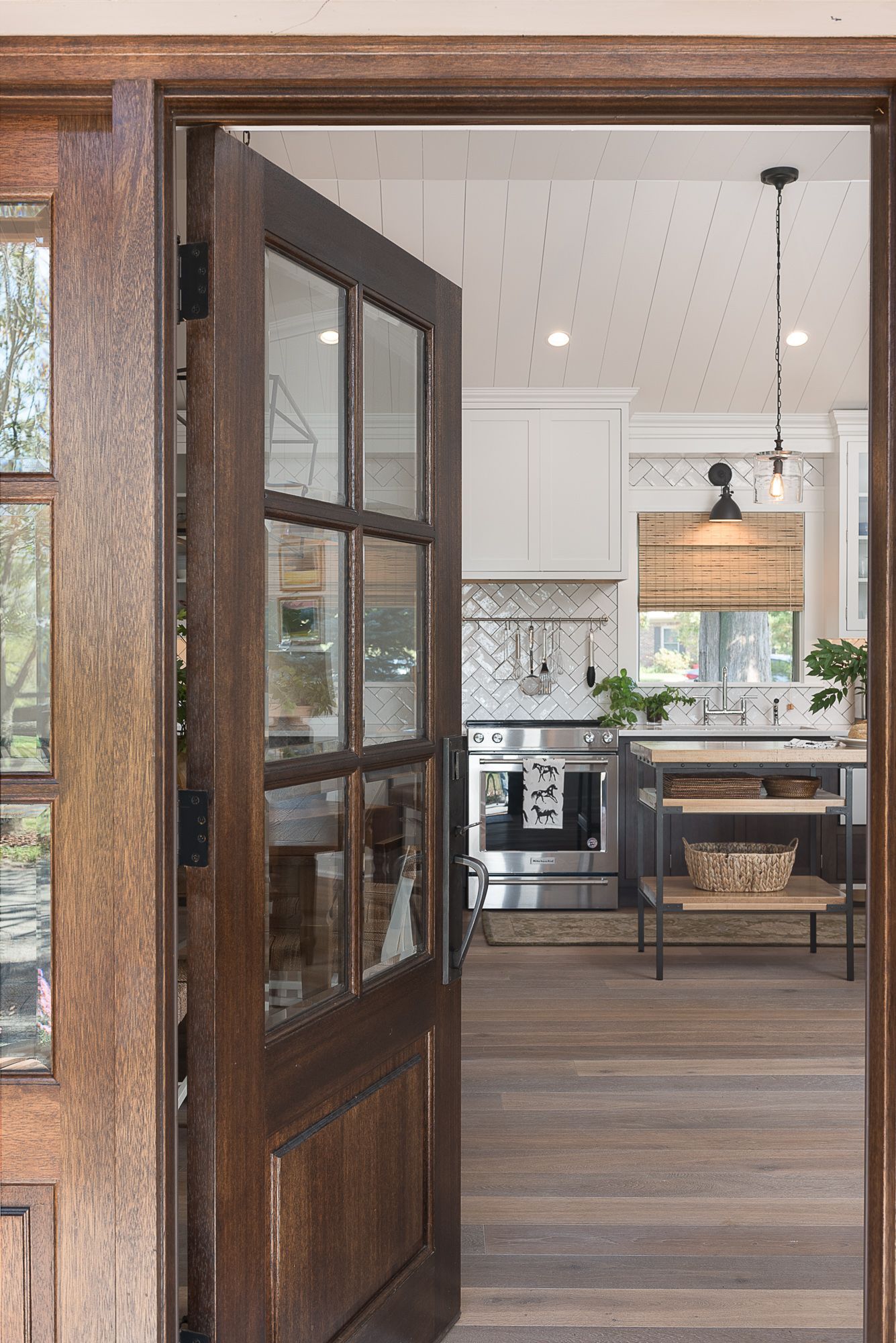 A wooden door is open to a kitchen with white cabinets and stainless steel appliances.