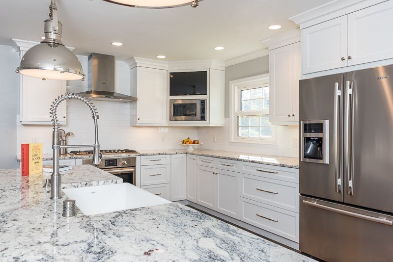A kitchen with white cabinets , granite counter tops , stainless steel appliances and a stainless steel refrigerator.