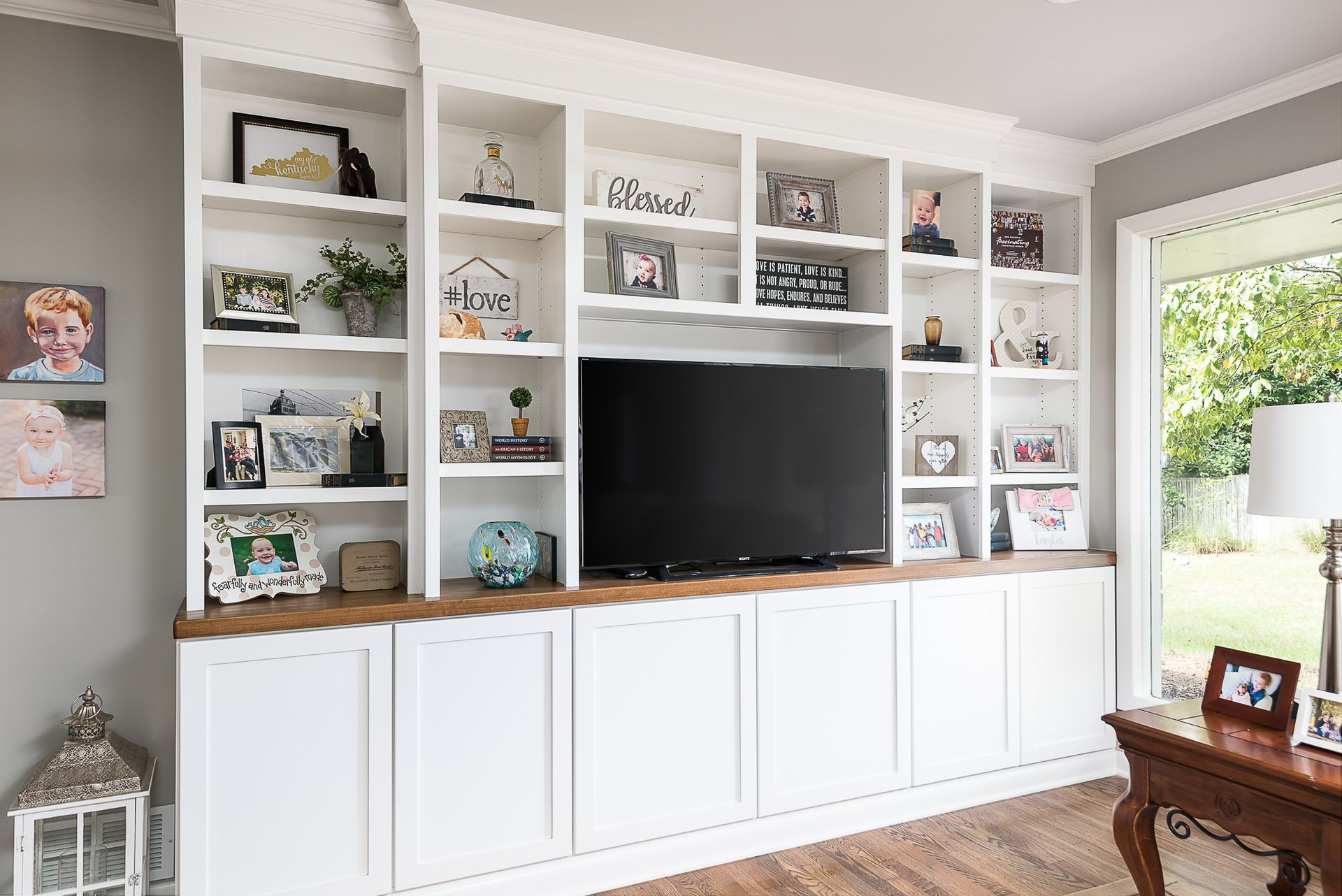 A living room with lots of shelves and a flat screen tv.