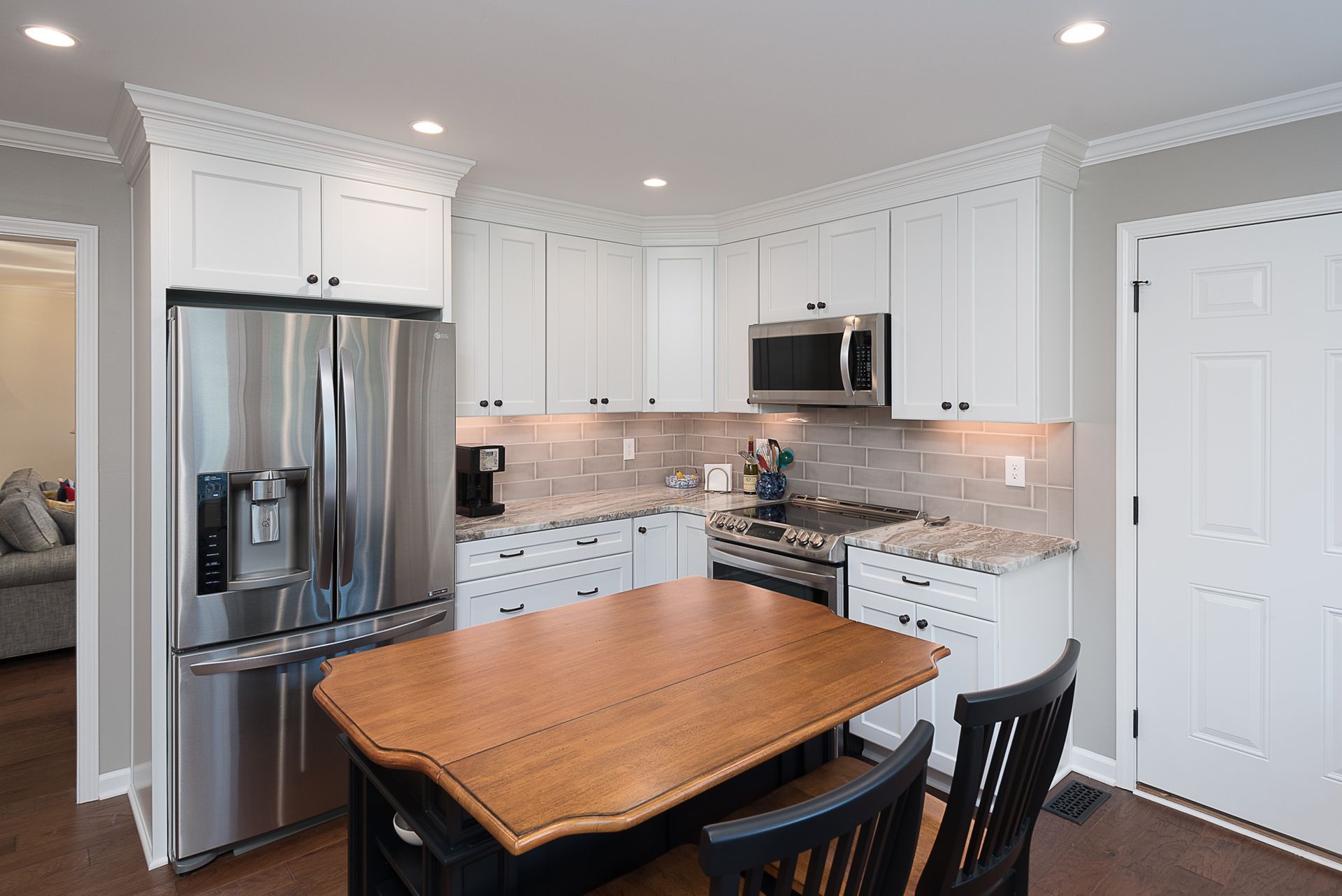 A kitchen with white cabinets , stainless steel appliances , a table and chairs.