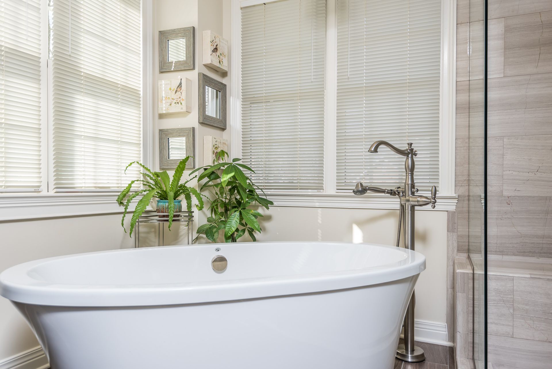 A bathtub in a bathroom next to a window with blinds.