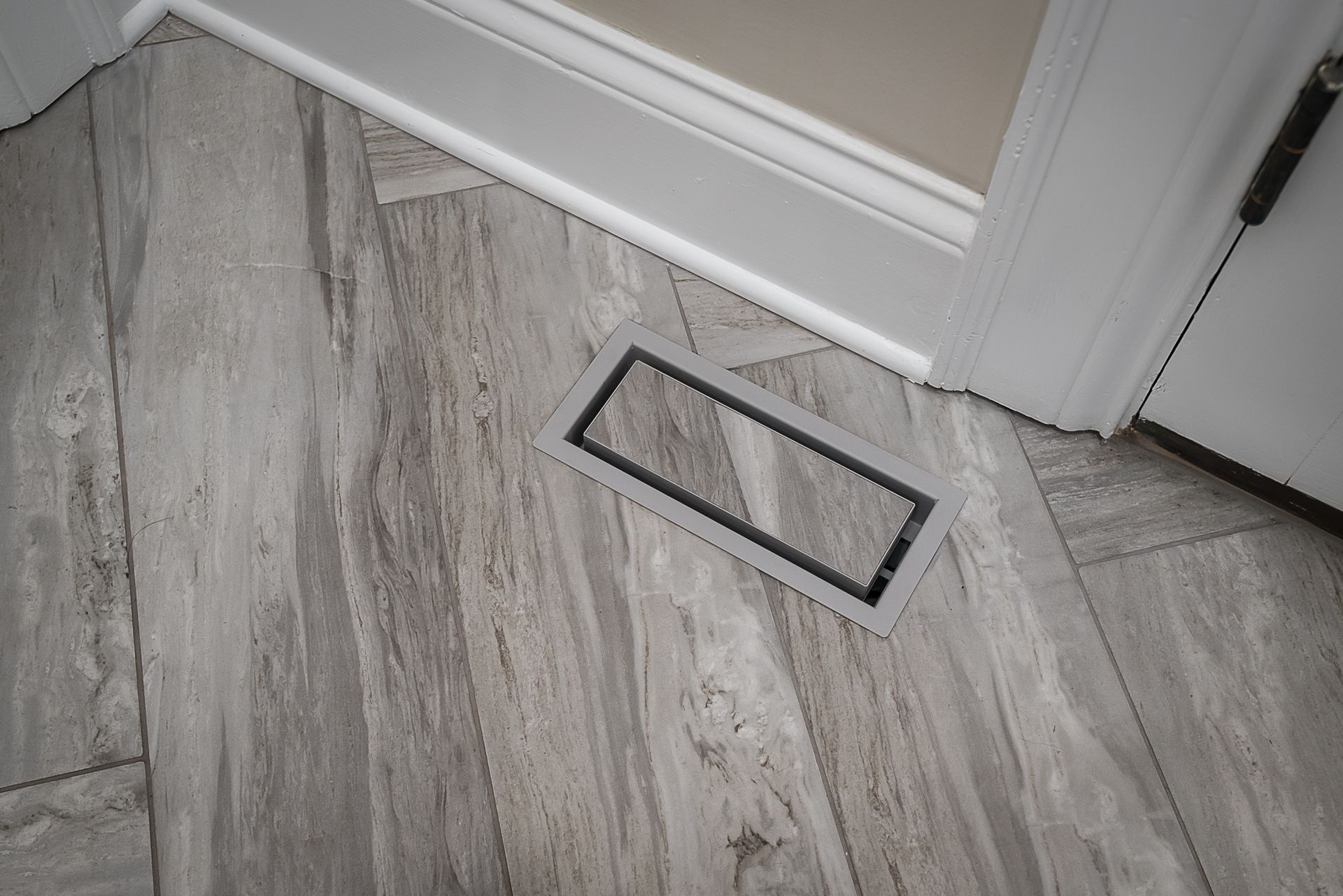 There is a vent on the floor next to a door.
