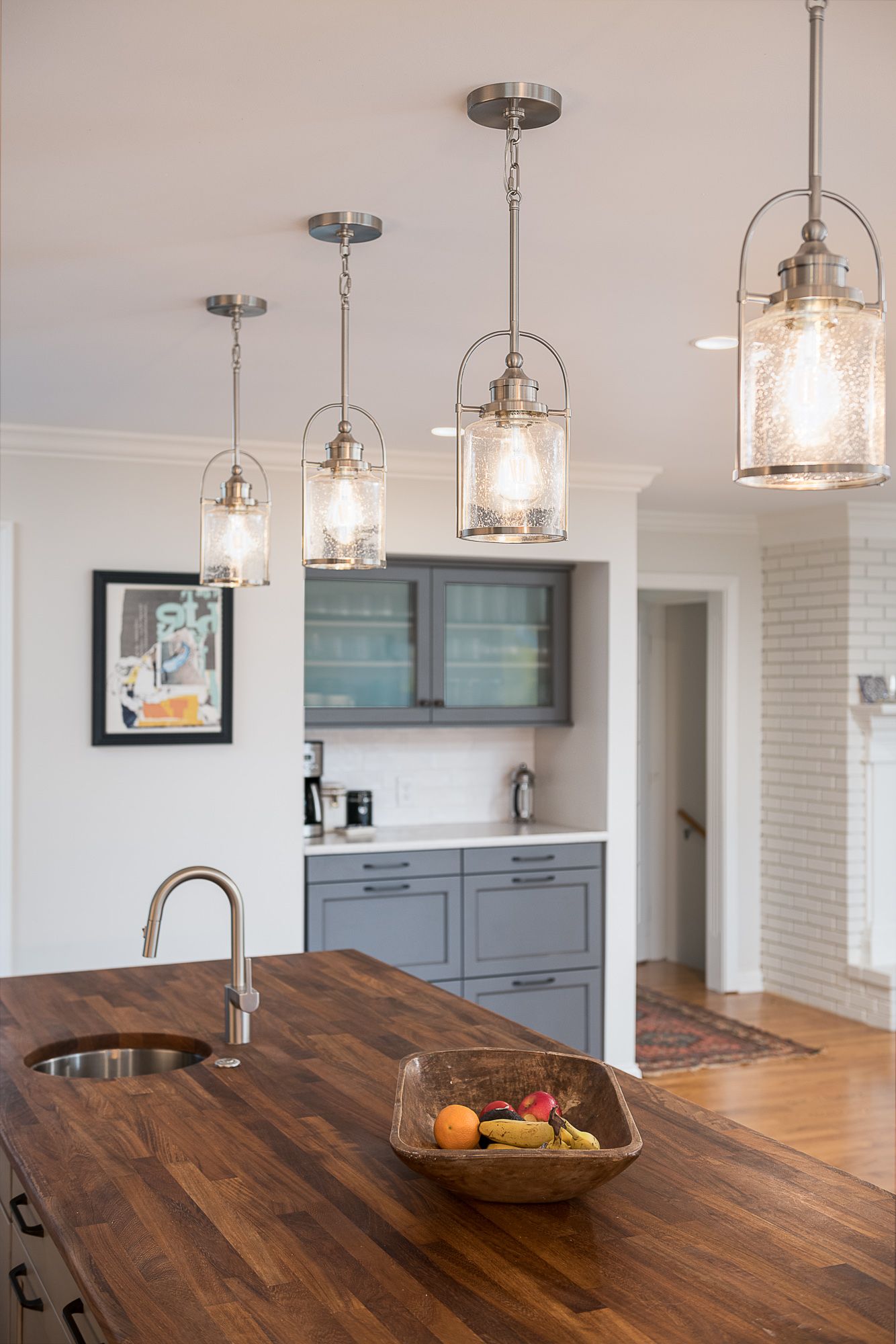 There is a bowl of fruit on the counter in the kitchen.