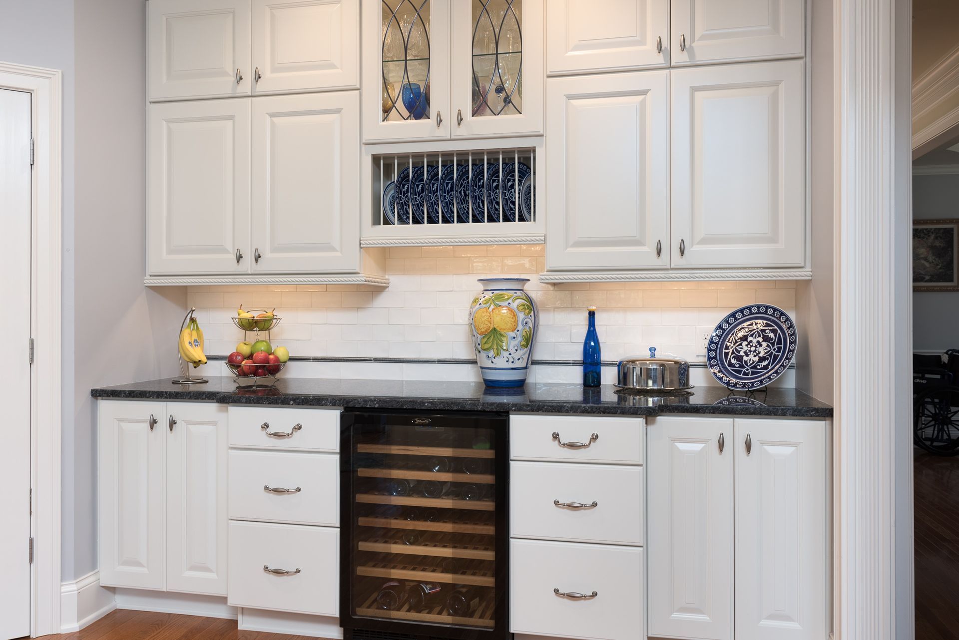 A kitchen with white cabinets and a wine cooler