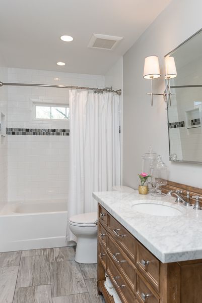 A bathroom with a sink , toilet , tub and mirror.