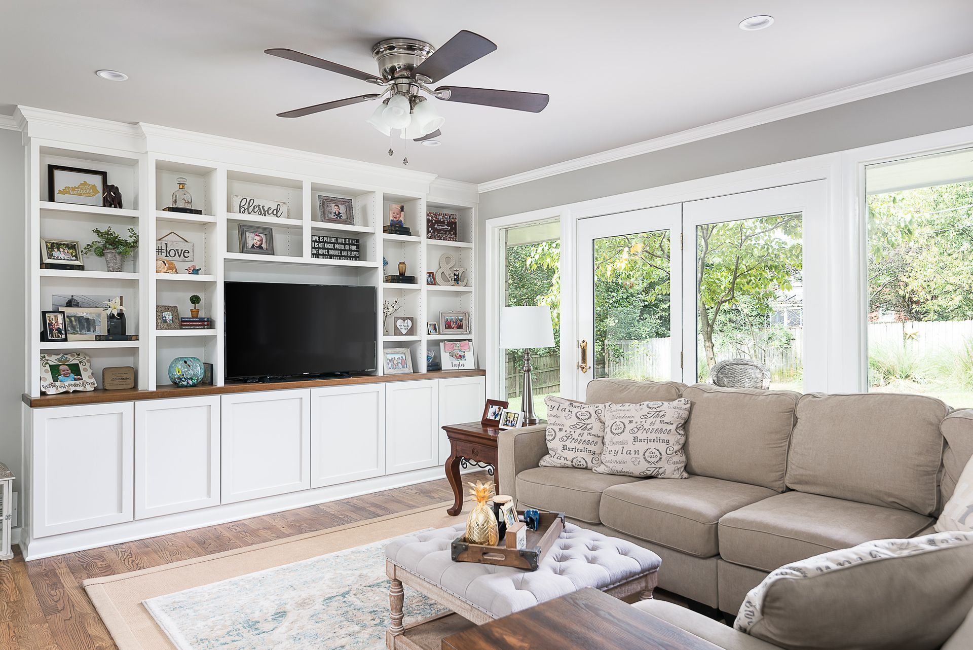 A living room with a couch , television , and ceiling fan.