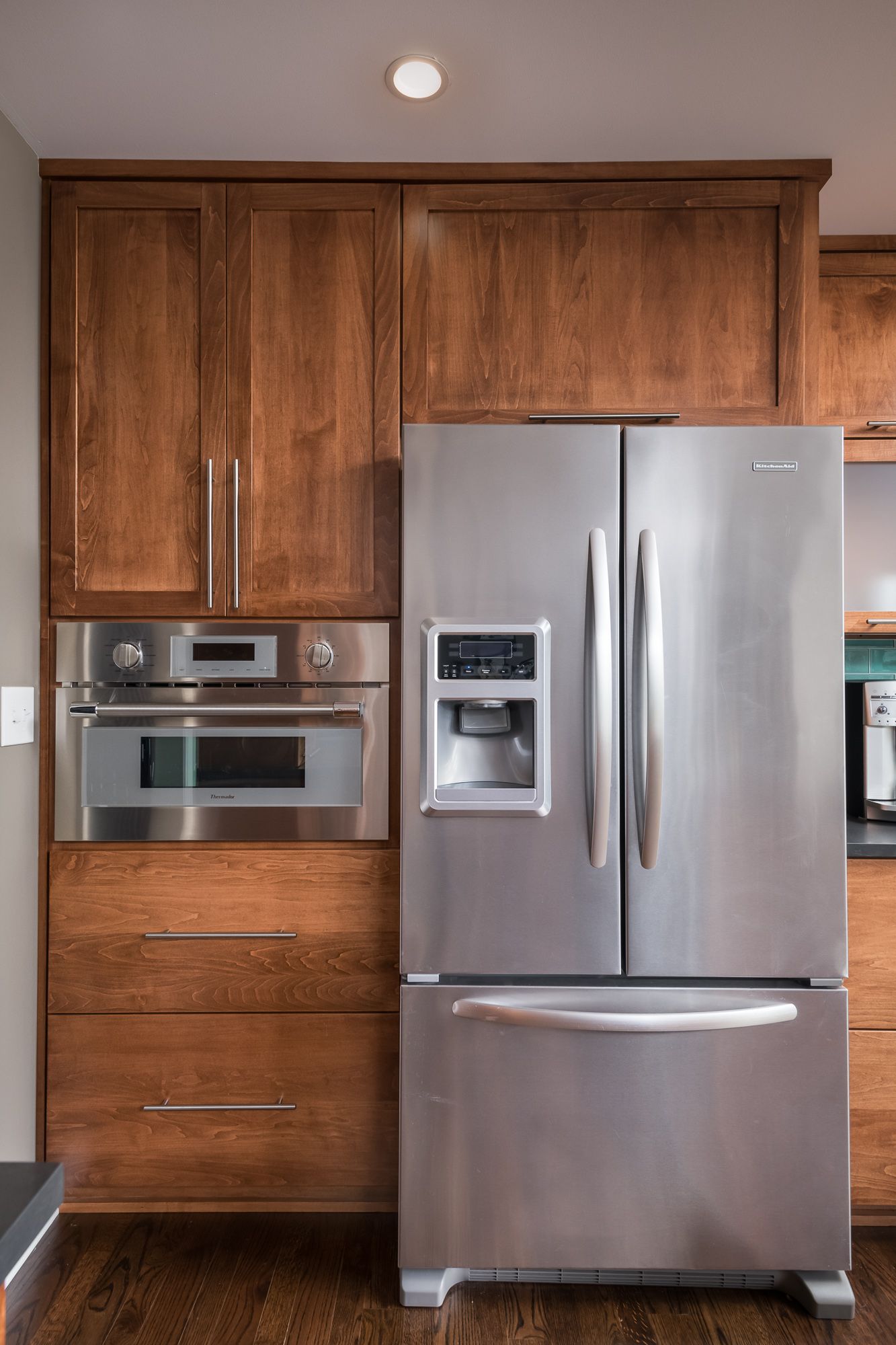 A stainless steel refrigerator is in a kitchen with wooden cabinets.