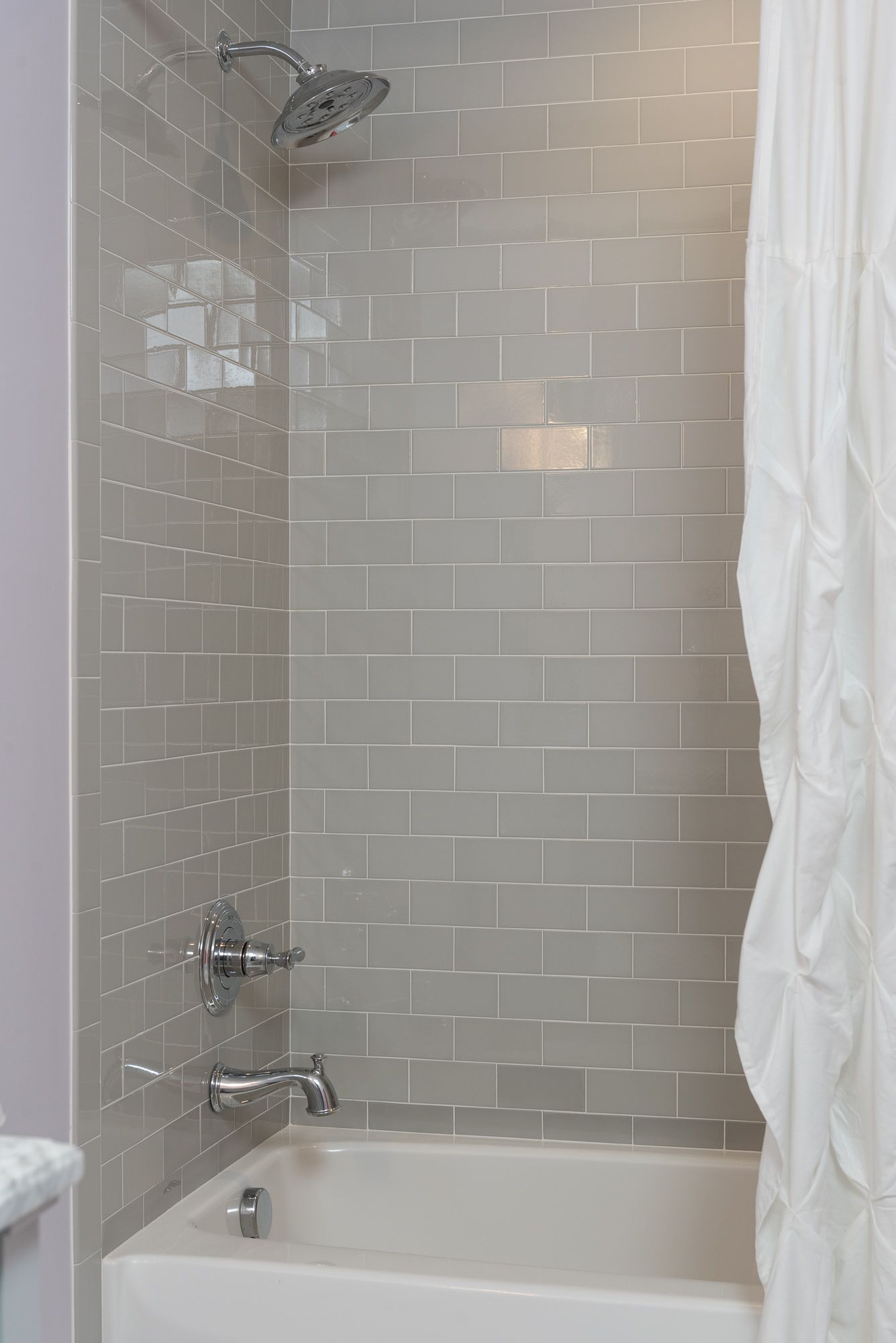 There is a bathtub in the shower with a shower head.