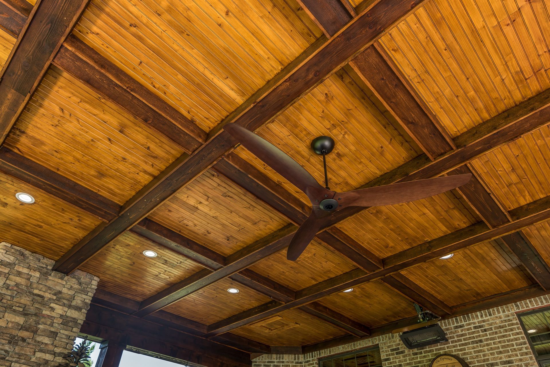 A wooden ceiling with a ceiling fan hanging from it.