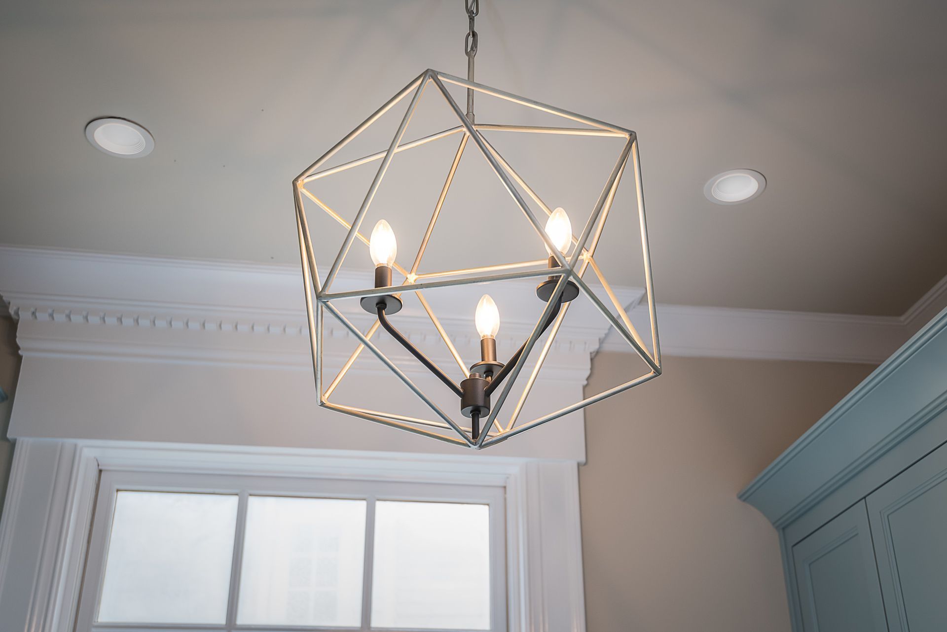 A chandelier is hanging from the ceiling in front of a window.