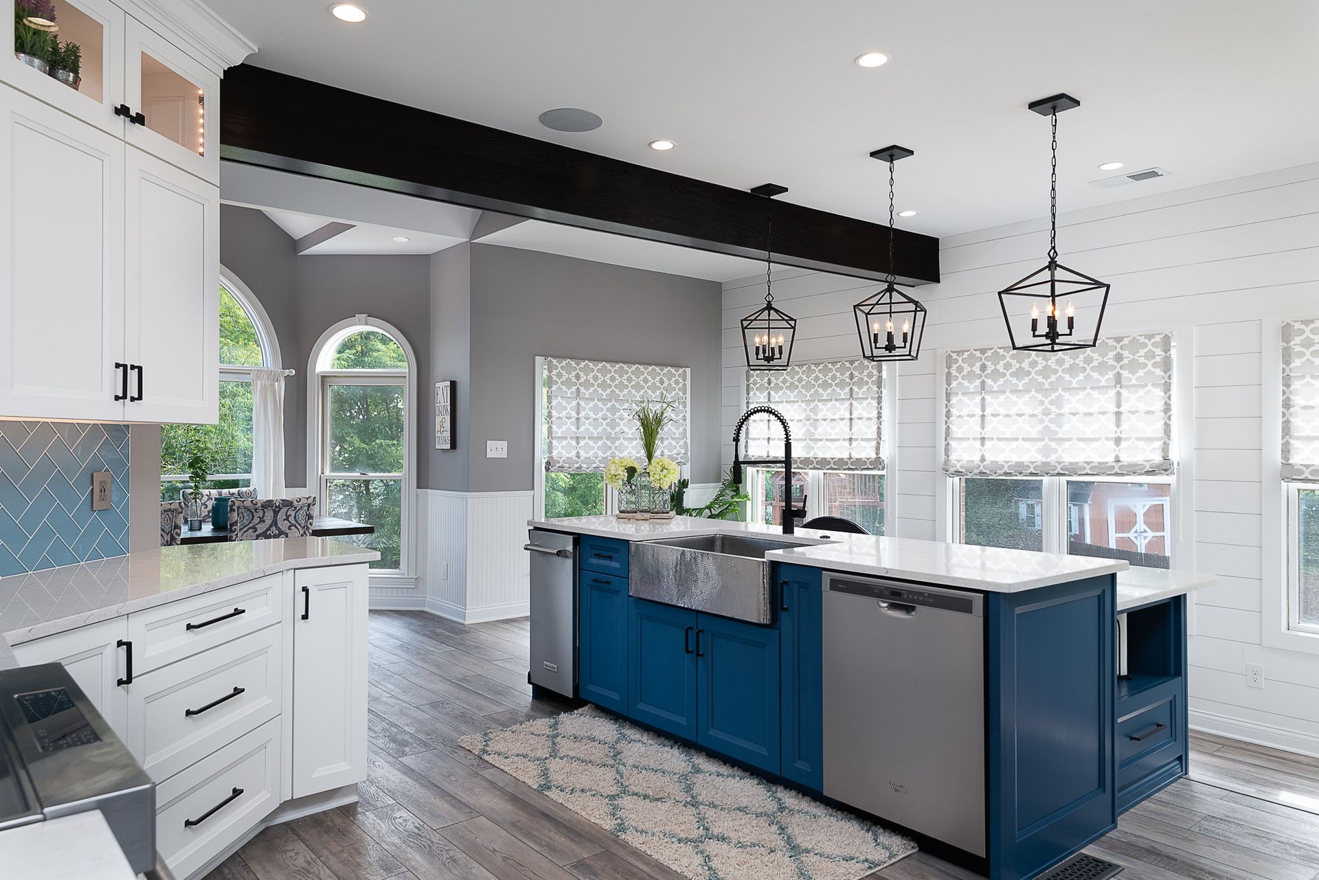 A kitchen with blue cabinets , white cabinets , stainless steel appliances and a large island.