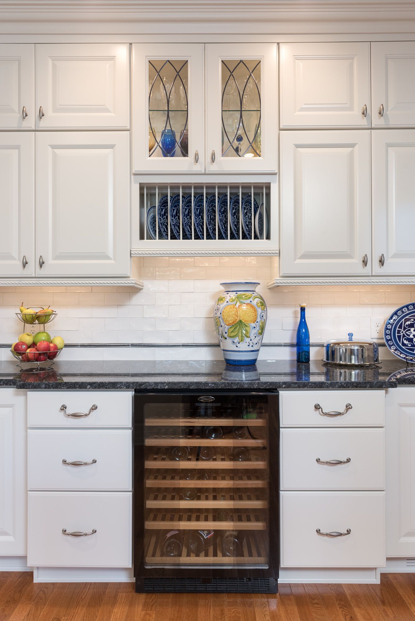 A kitchen with white cabinets and a wine cooler