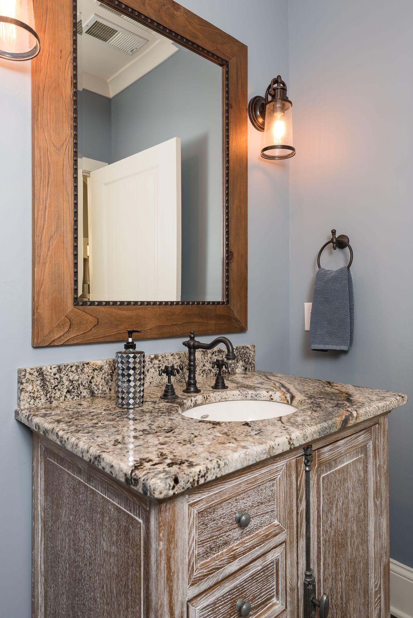 A bathroom with a sink , mirror and light.