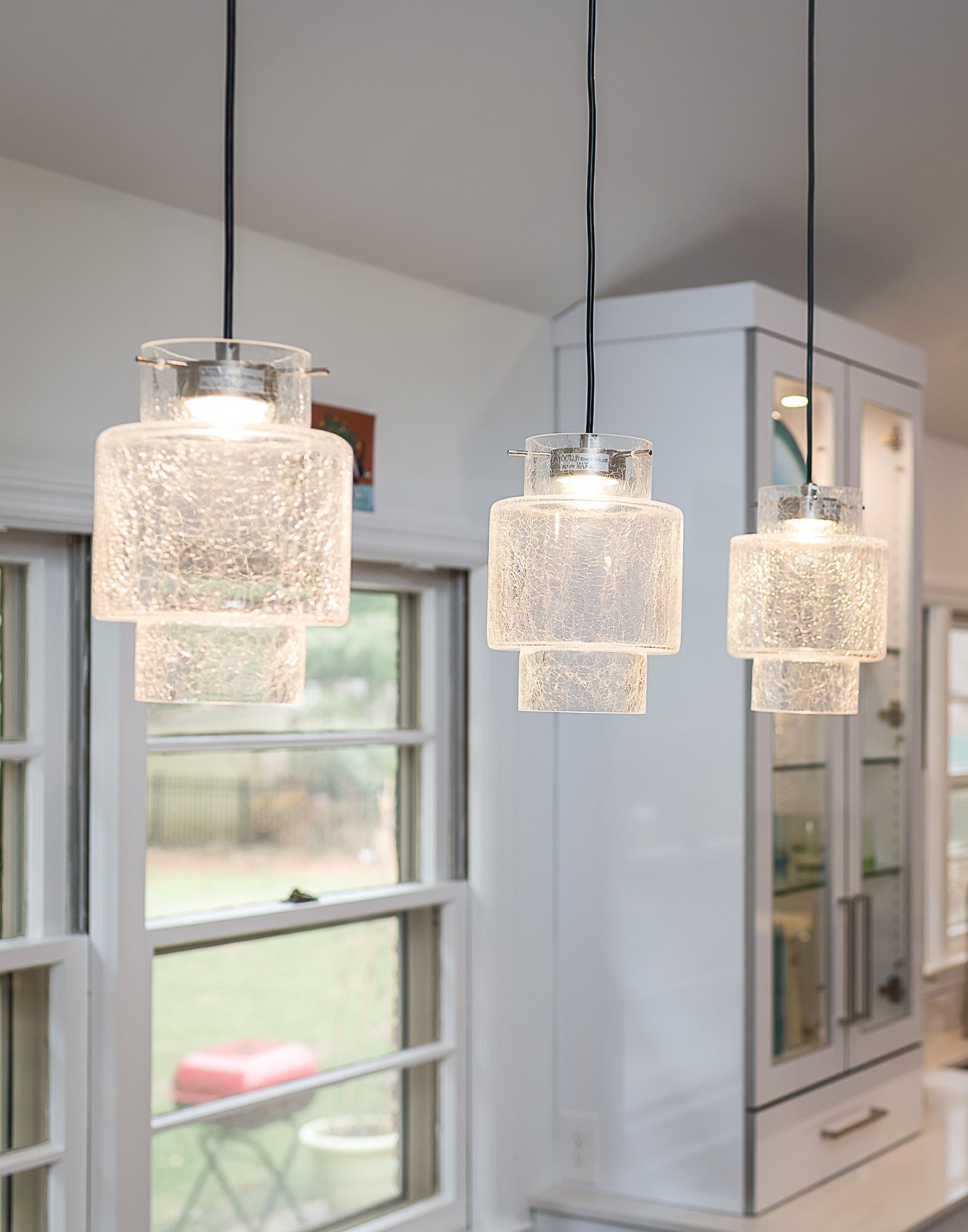 A kitchen with three pendant lights hanging from the ceiling