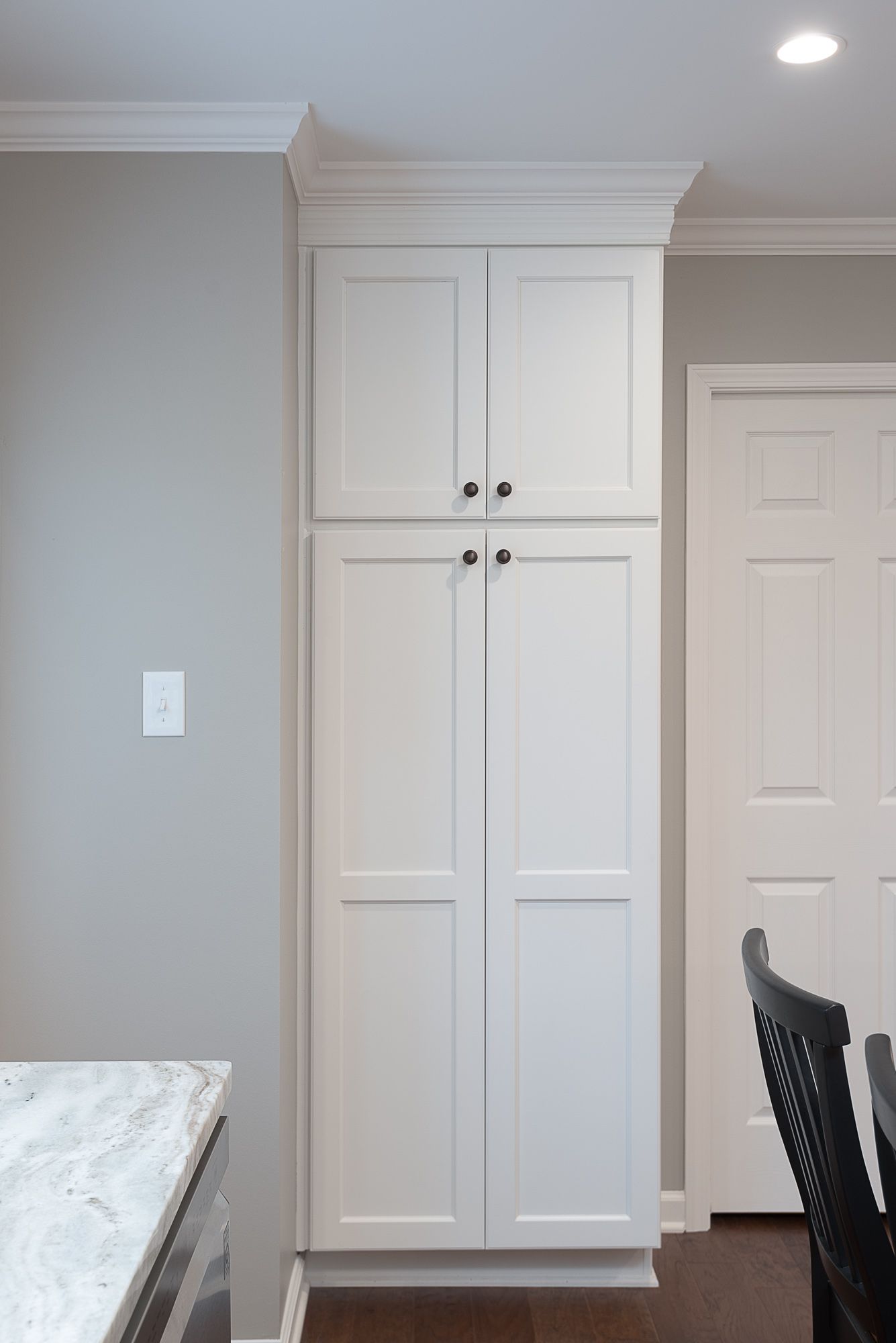 A kitchen with white cabinets and a marble counter top.