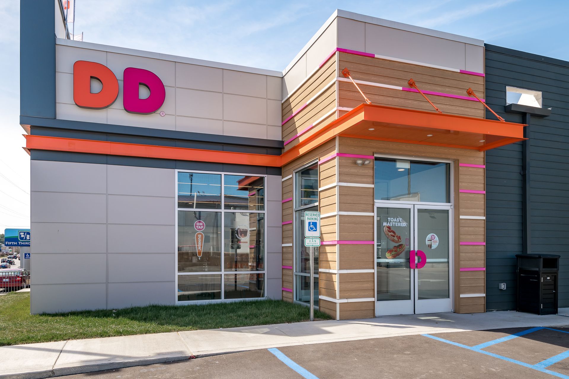 A dunkin donuts restaurant with a parking lot in front of it.