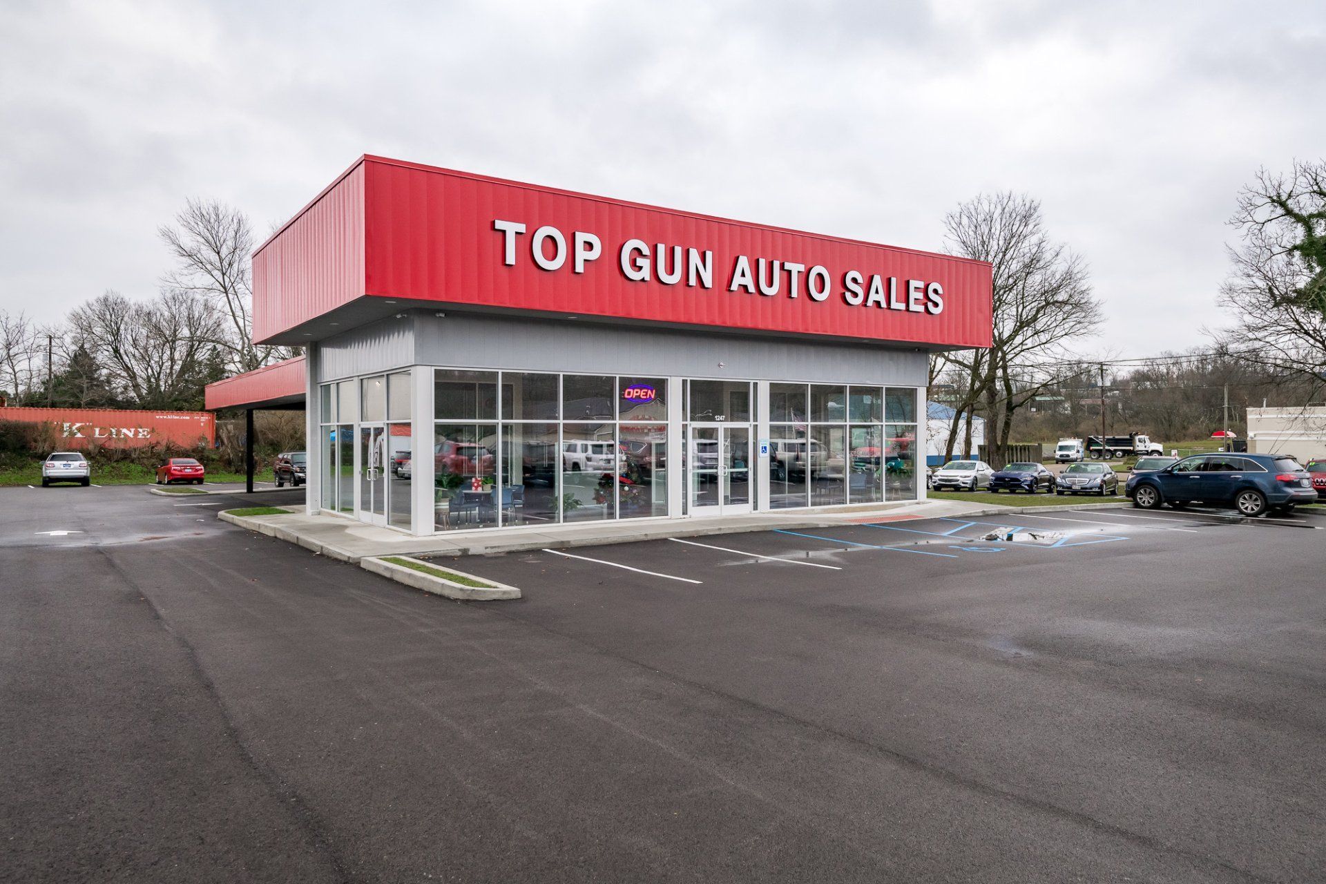 Top Gun Auto Sales building with red roof and blacktop parking lot